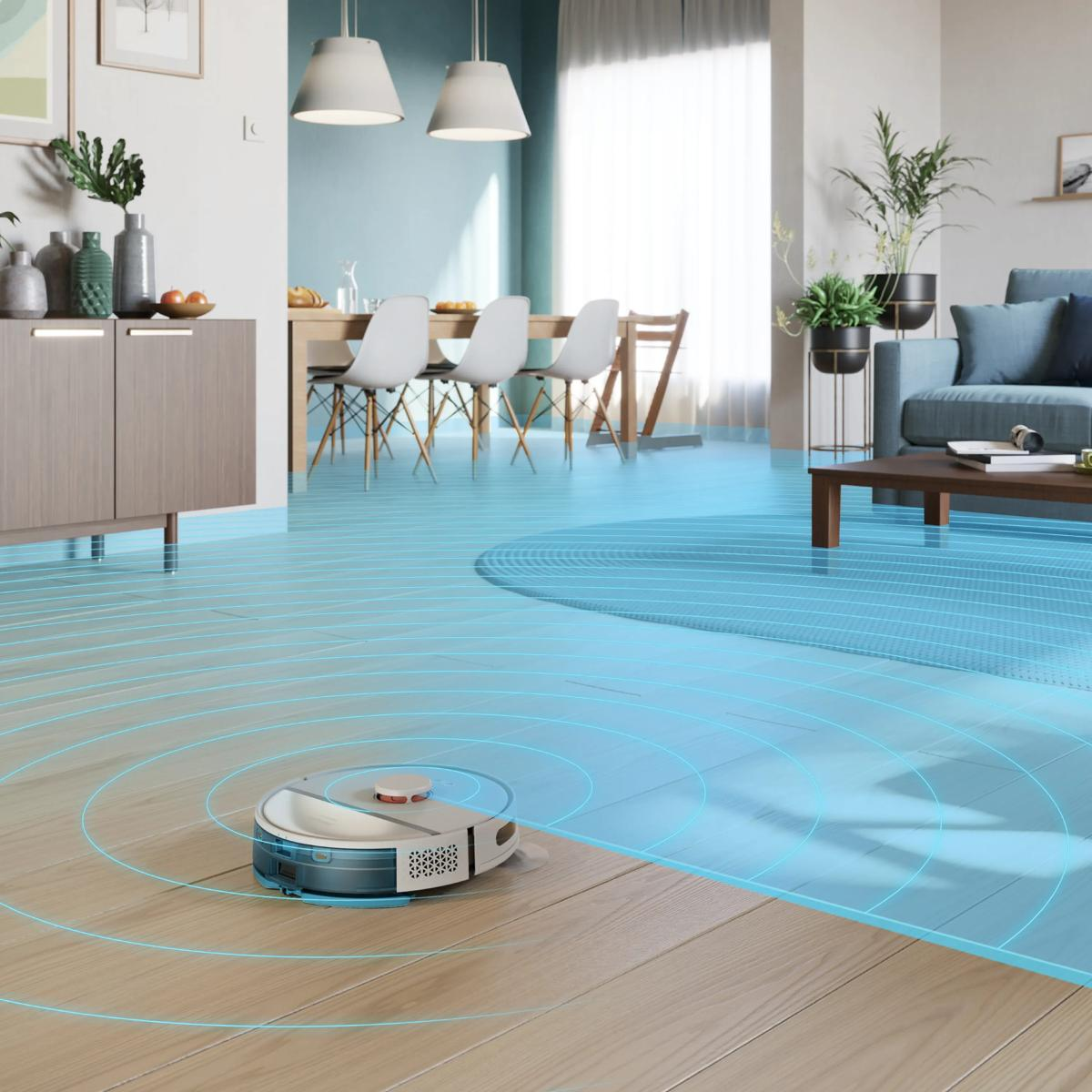 Robot süpürge, yemek odası ve kanepeli modern bir oturma alanında ahşap zemini temizliyor.