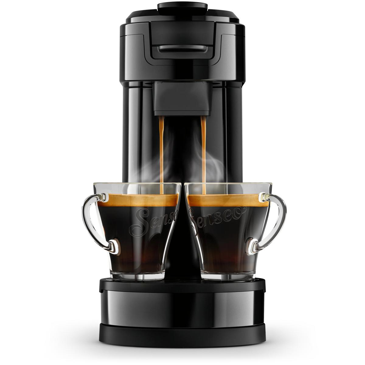 Eine schwarze Kaffeemaschine brüht zwei Tassen Espresso mit Schaum. Dampf steigt auf.