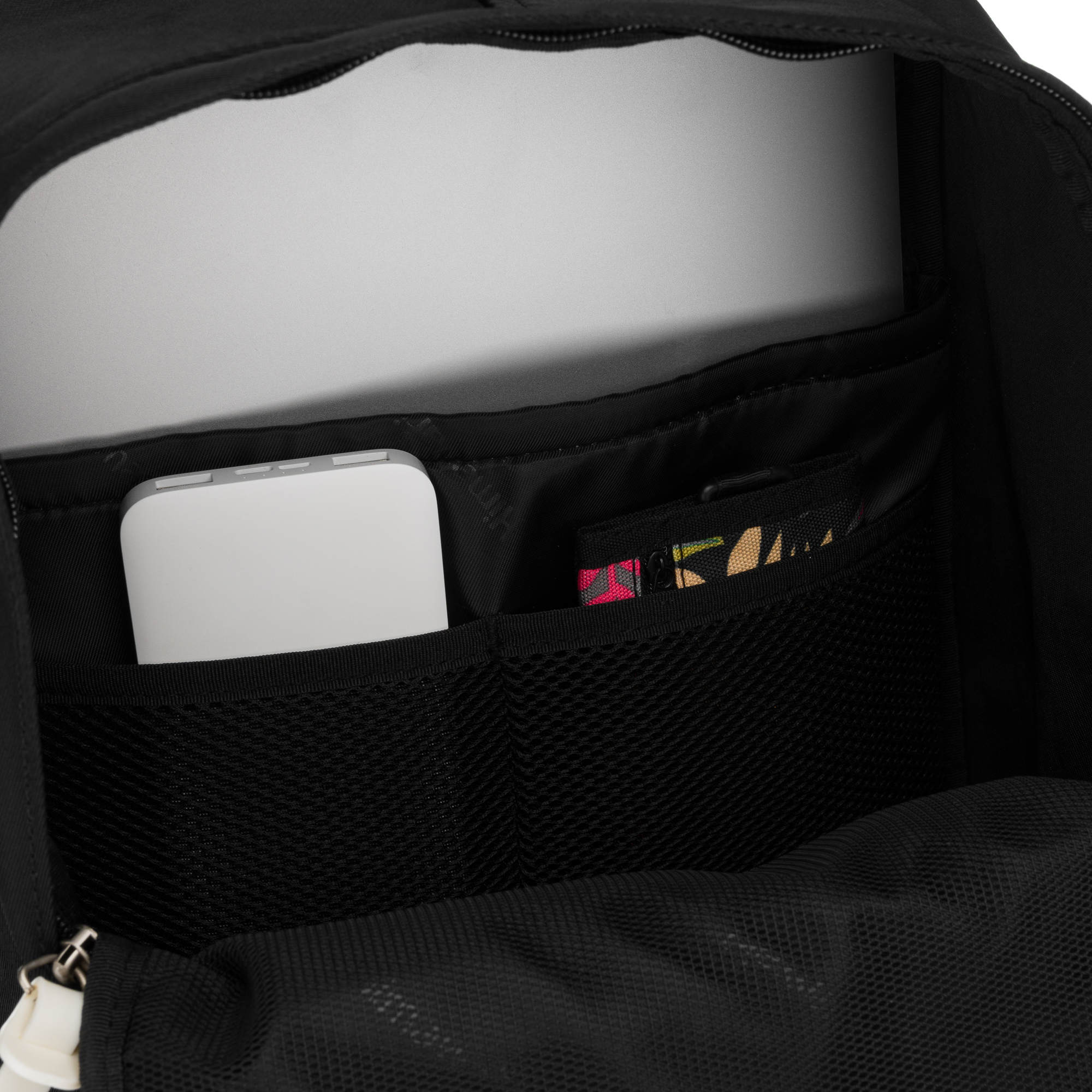 Biały smartfon i laptop w czarnym plecaku.