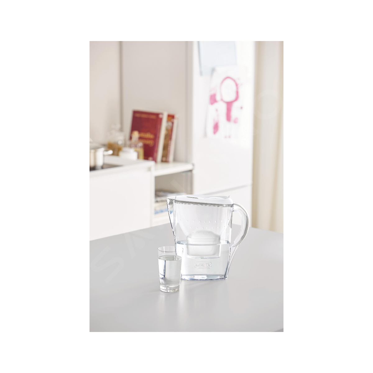 Przezroczysty dzbanek filtrujący wodę ze szklanką wody na stole.