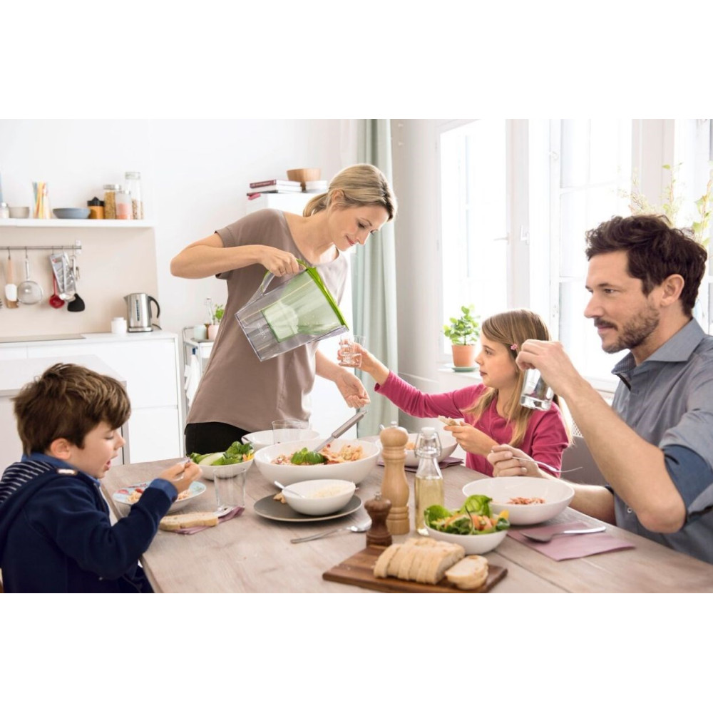 Rodzina je przy stole. Matka nalewa wodę córce. Kuchnia.