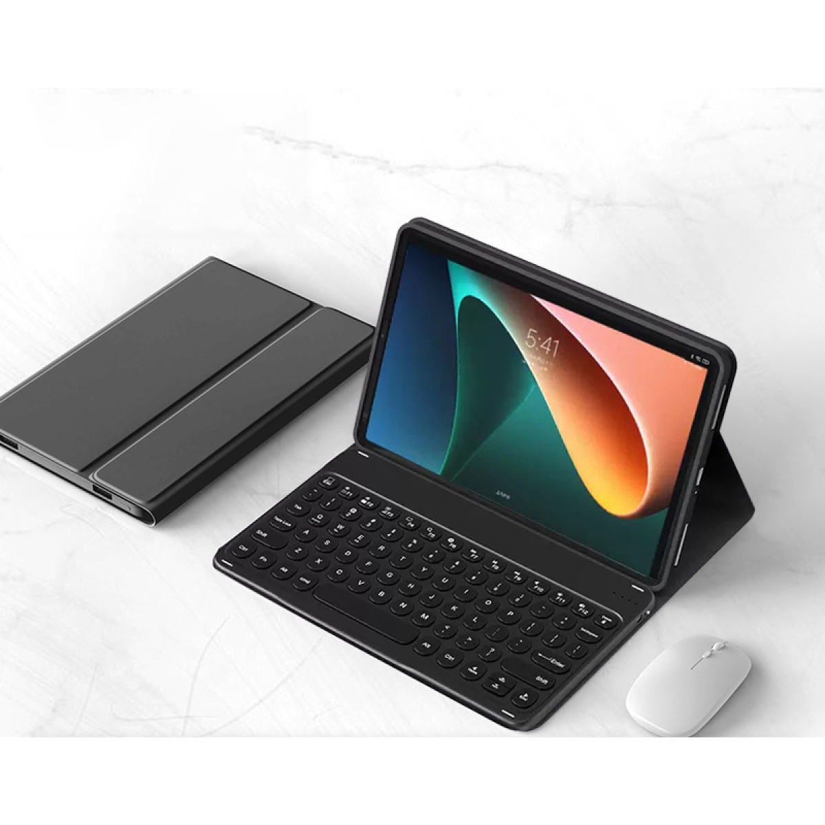 Ein schwarzes Tablet mit Tastatur und Maus auf Marmoroberfläche.