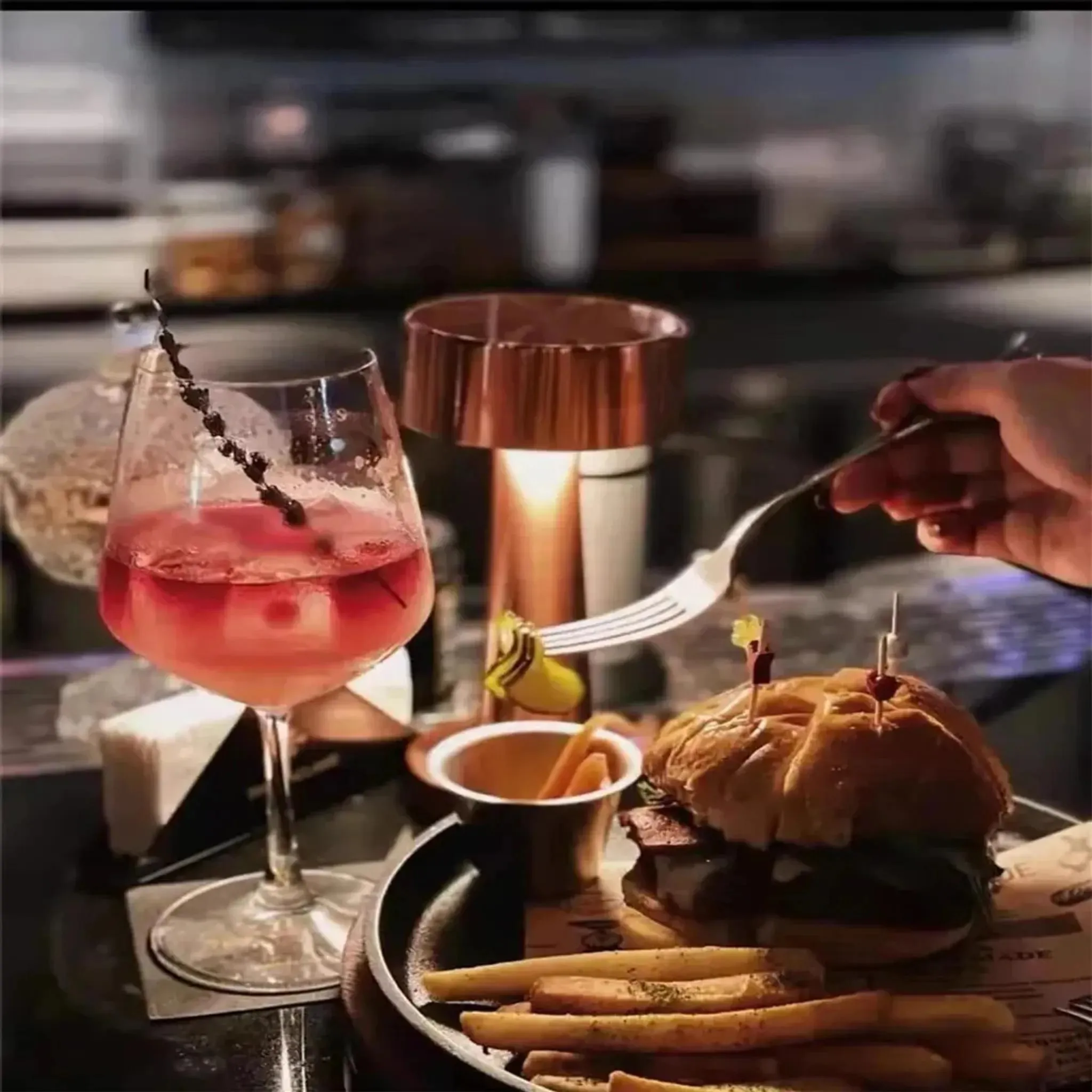Ein Burger mit Pommes und ein Glas roter Limonade auf einem Tisch.