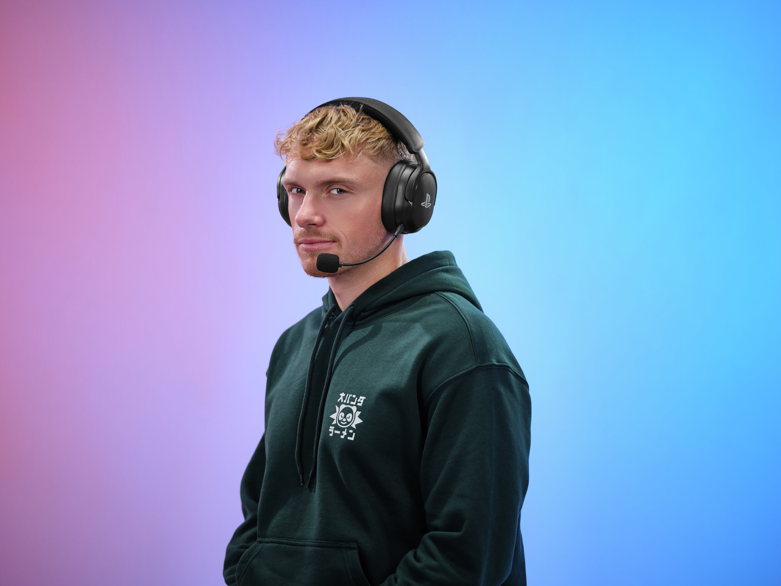 Ein Mann mit blonden Haaren trägt Kopfhörer und einen Hoodie. Farbverlauf im Hintergrund.