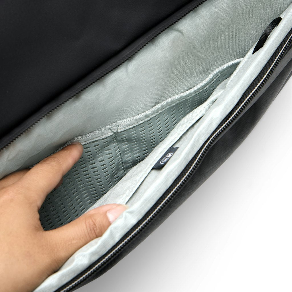 Hand reaches into a black bag with a light gray interior and mesh pockets.