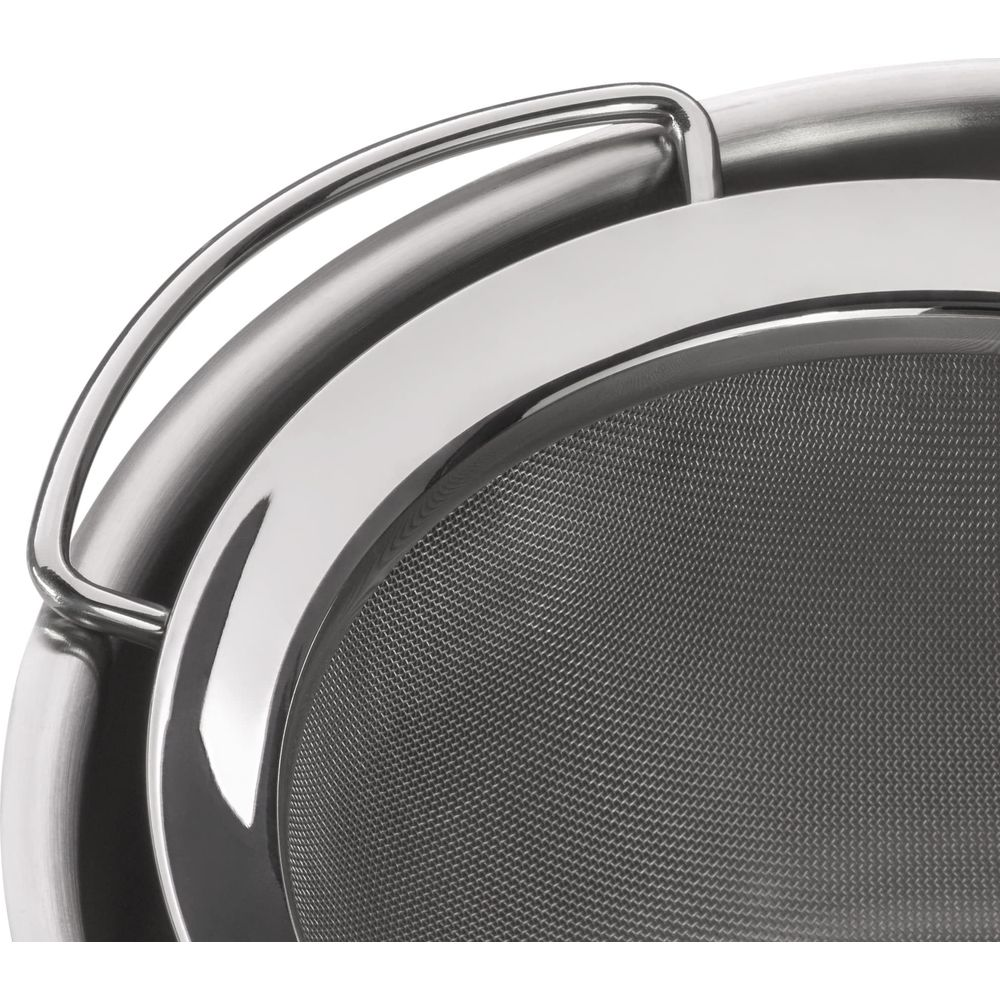 Zbliżenie na srebrne sitko z siateczkowym wzorem i zakrzywionym uchwytem.