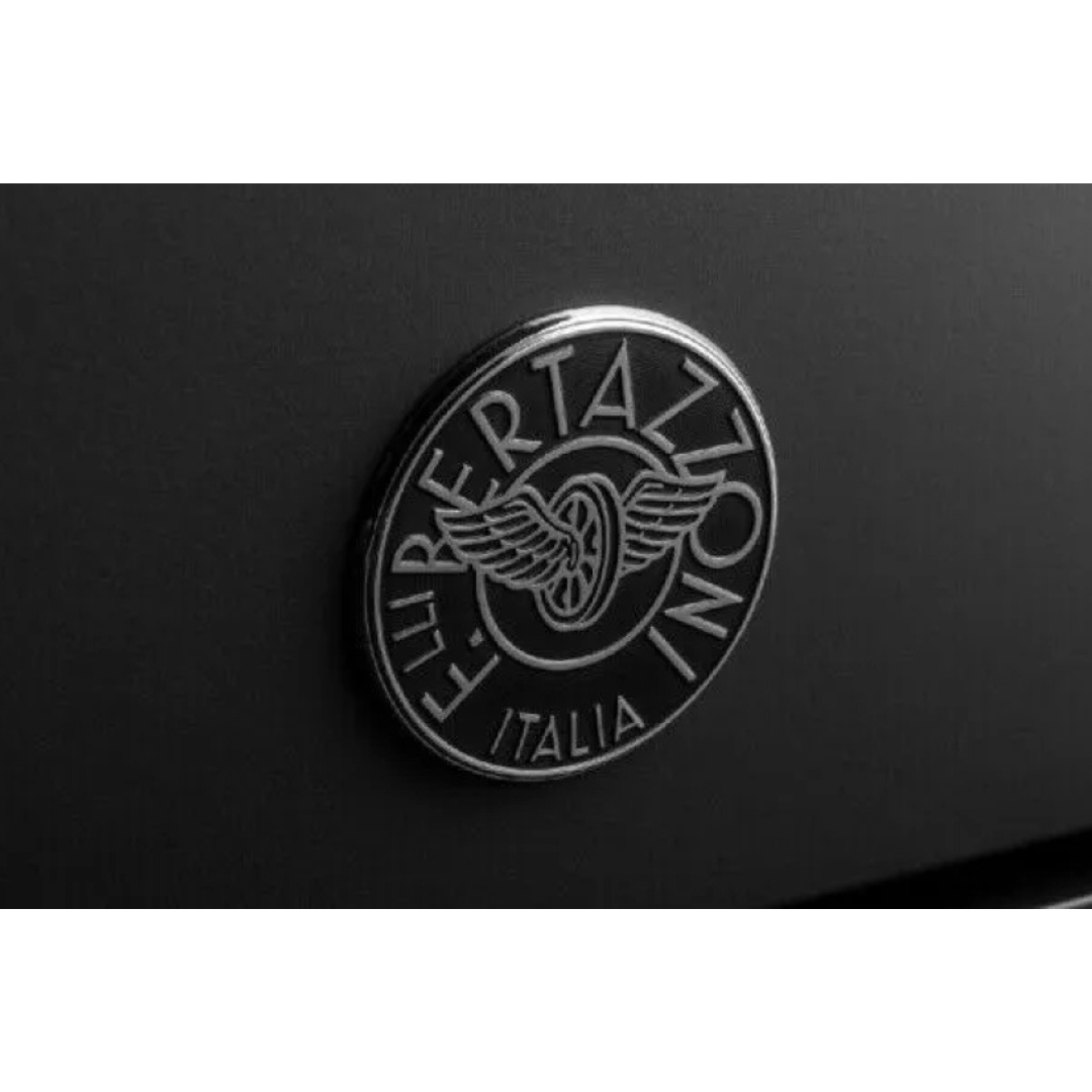 Emblema argentato su sfondo nero con ruota alata e scritte.