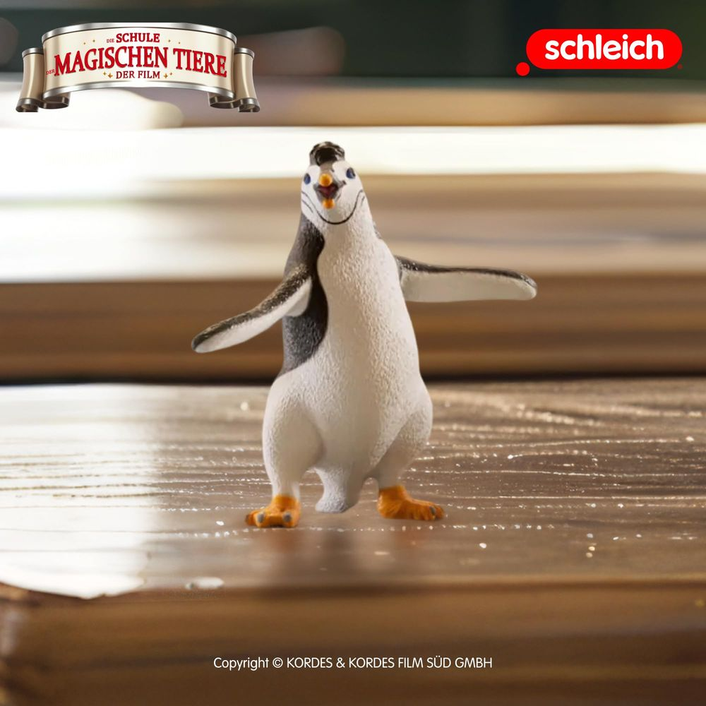 Una figura di pinguino Schleich su una superficie di legno. Uno stendardo con testo in alto a sinistra.