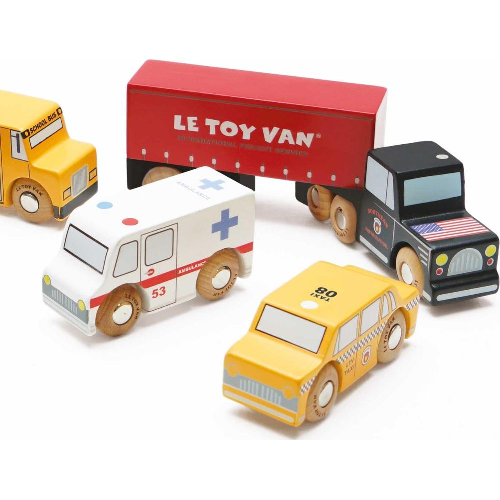 Véhicules jouets en bois : bus scolaire, ambulance, taxi, camion noir, remorque rouge.