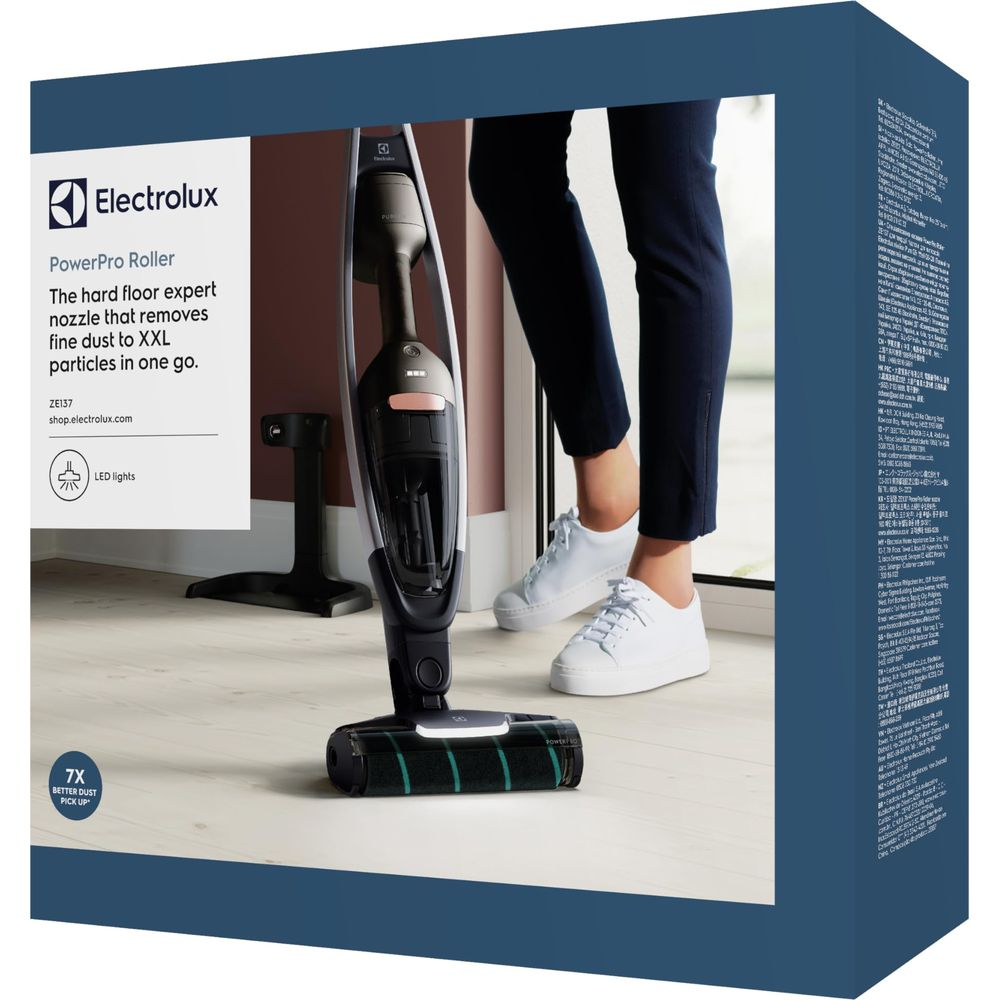 Une personne utilise un aspirateur sans fil Electrolux noir et gris sur sol dur.