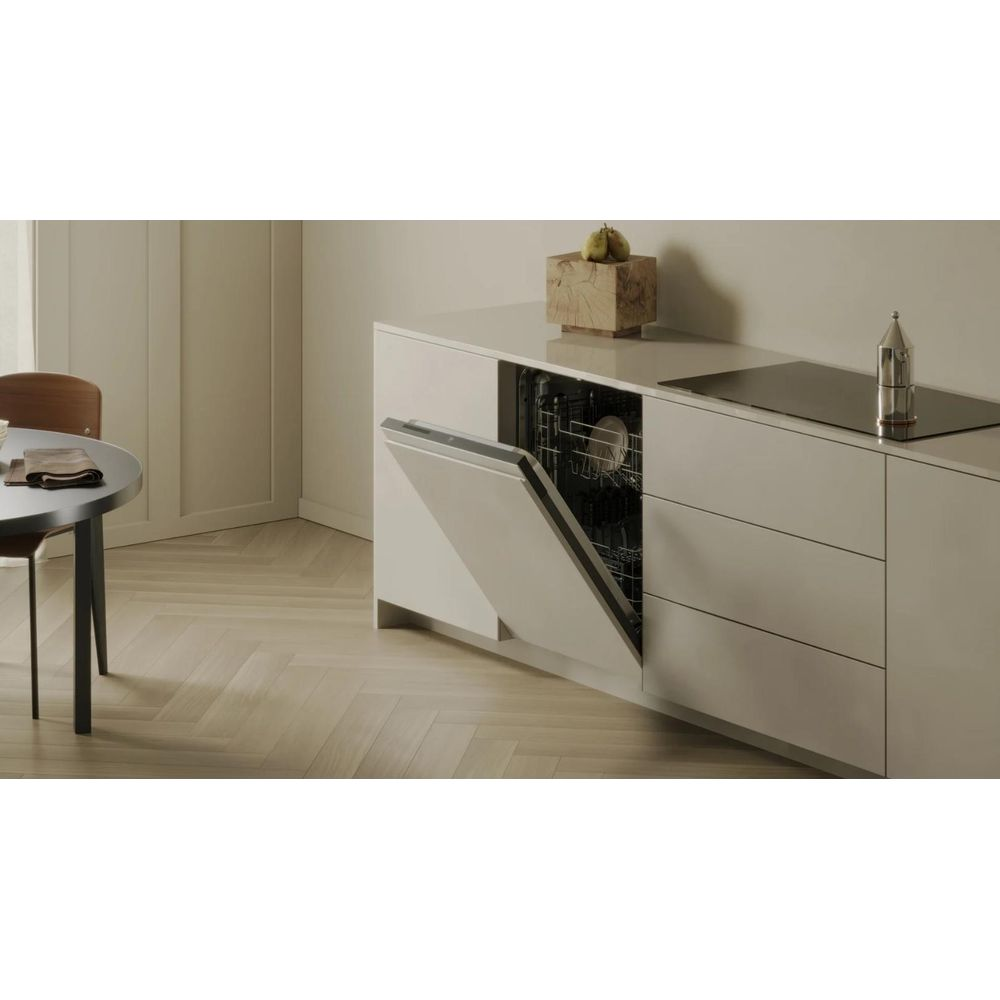 Una lavastoviglie aperta accanto a un piano di lavoro con piano cottura e decorazioni.