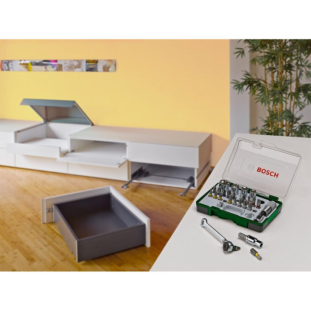 Une boîte à outils Bosch avec cliquet et embouts repose sur une table à côté d'un meuble TV blanc.