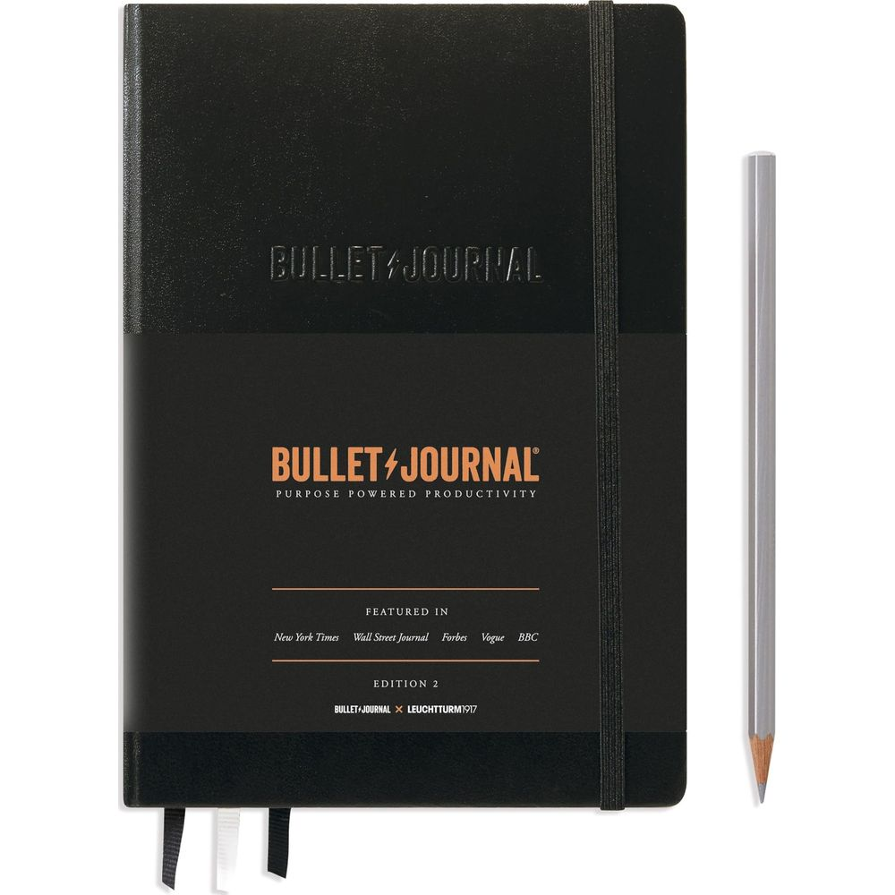 Agenda Bullet Journal nera con penna argentata. Testo sulla copertina.