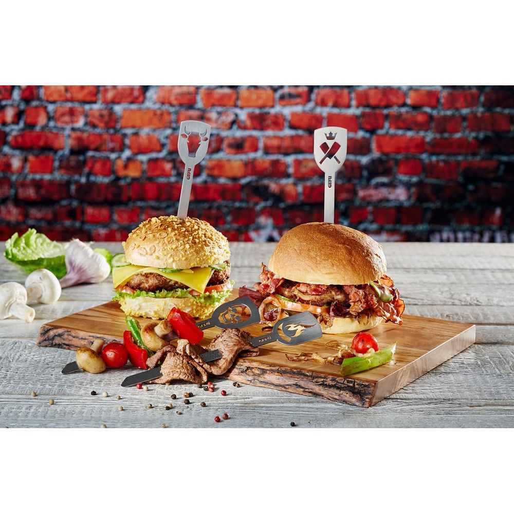 Due hamburger e spiedini di carne su tagliere di legno davanti a muro di mattoni.