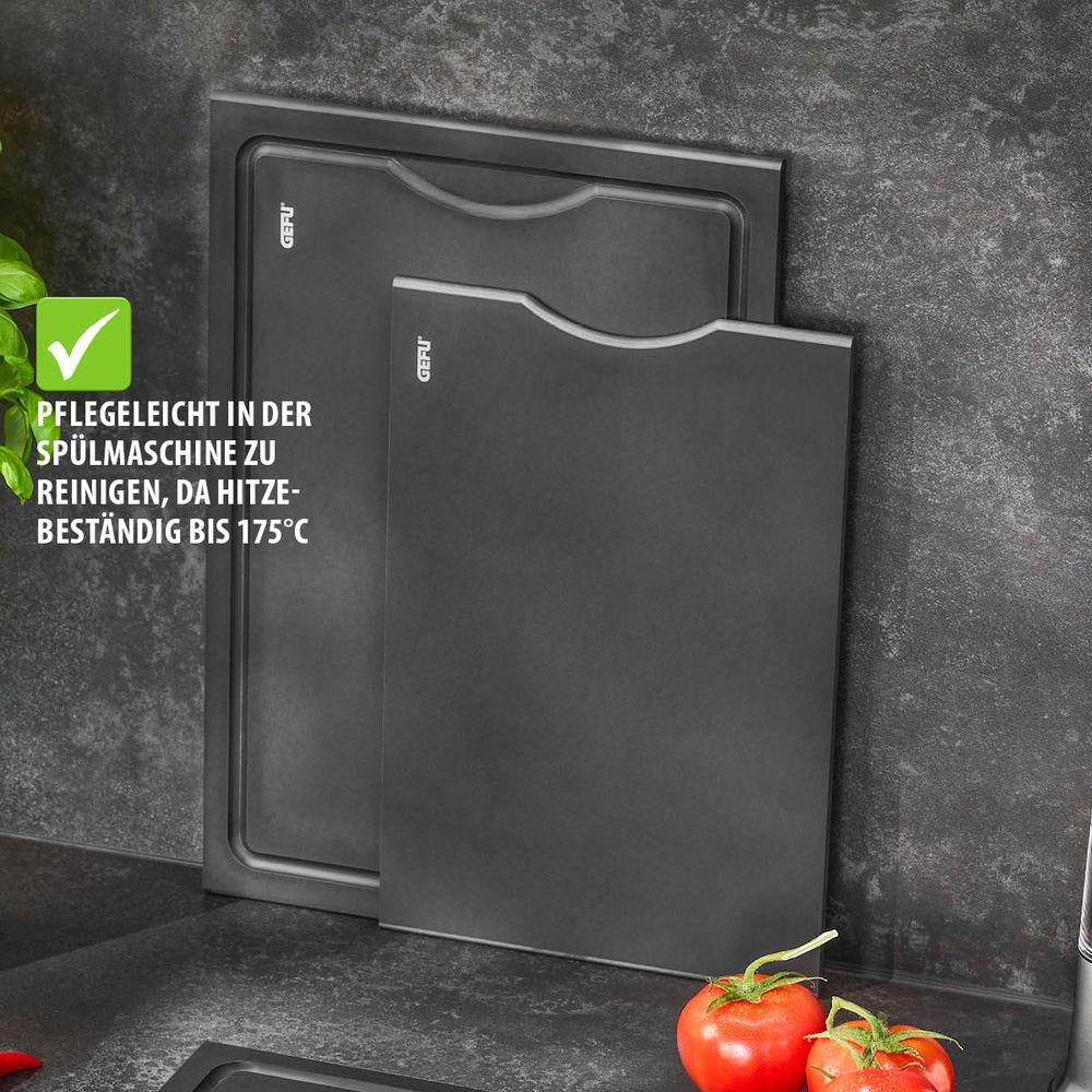 Zwei schwarze Schneidebretter von Gefu, eines hinter dem anderen, mit Tomaten im Vordergrund.