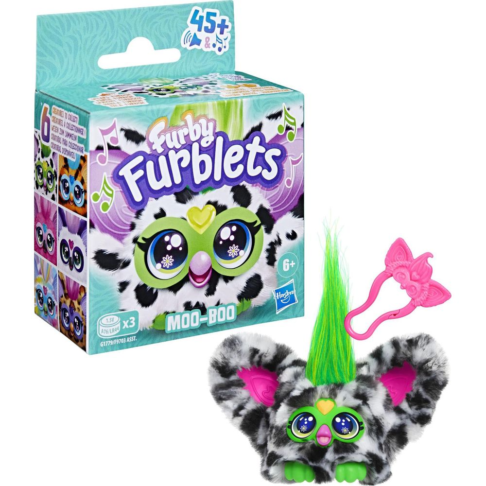 Un juguete Furblet peludo con estampado de vaca, una caja y un accesorio rosa.
