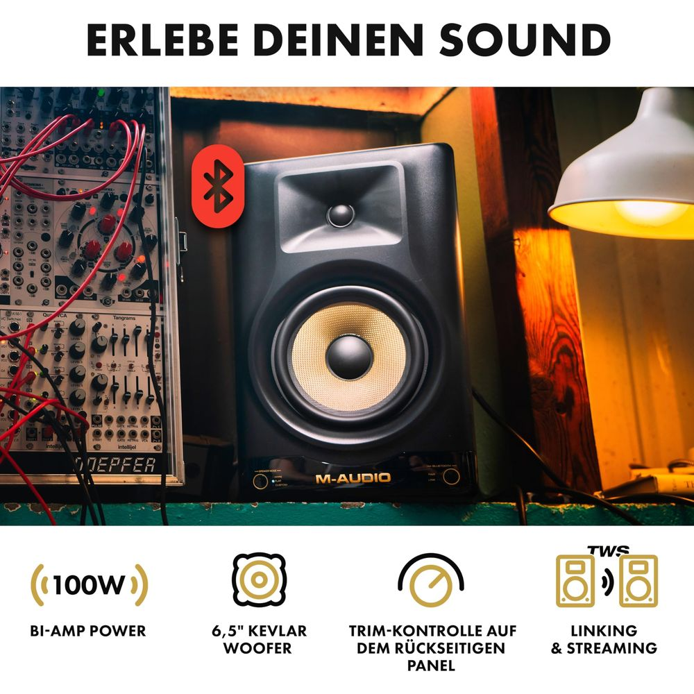 Un altoparlante M-Audio con Bluetooth accanto a un rack di sintetizzatori modulari.