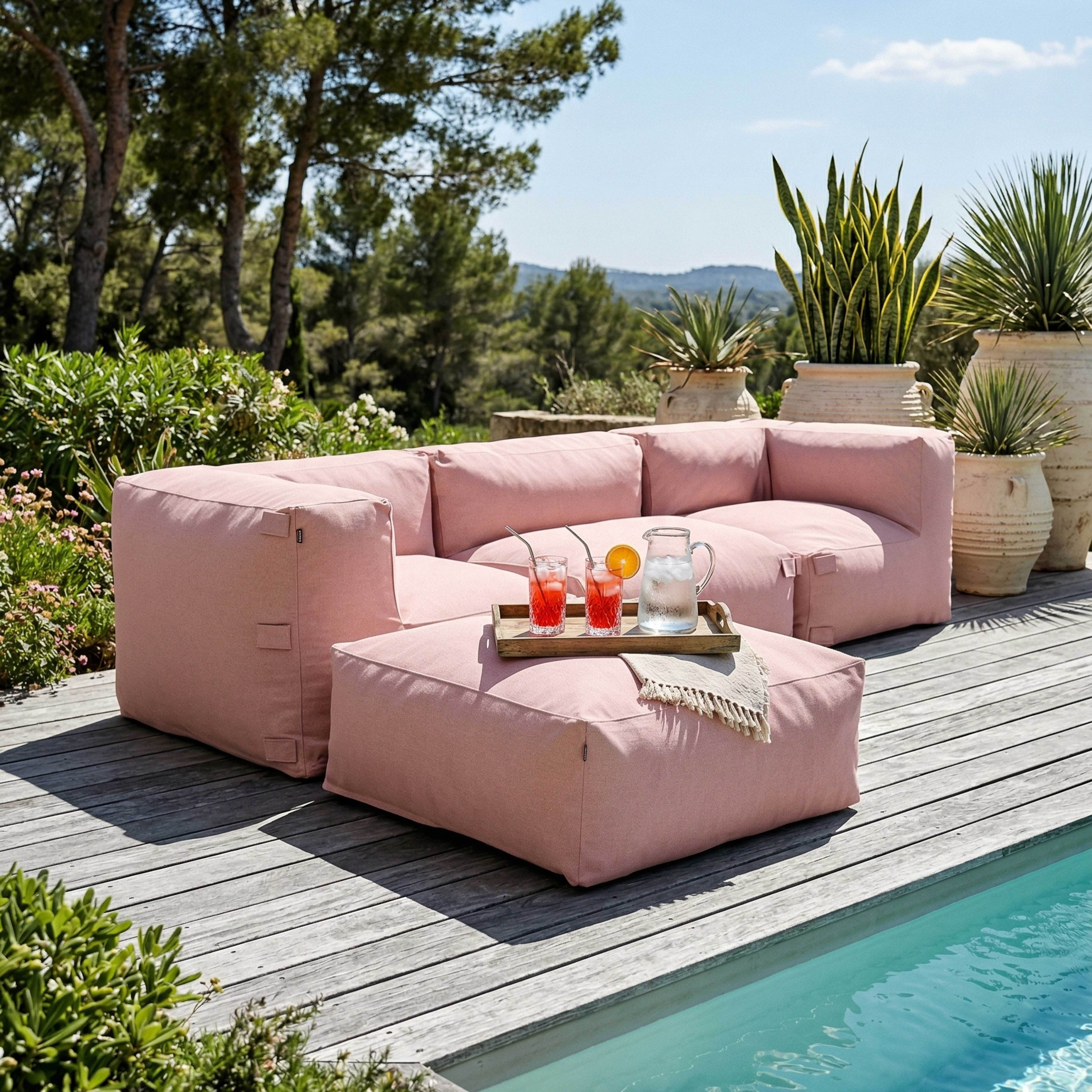 Ein rosa Lounge-Set am Pool mit Getränken auf einem Holztisch.
