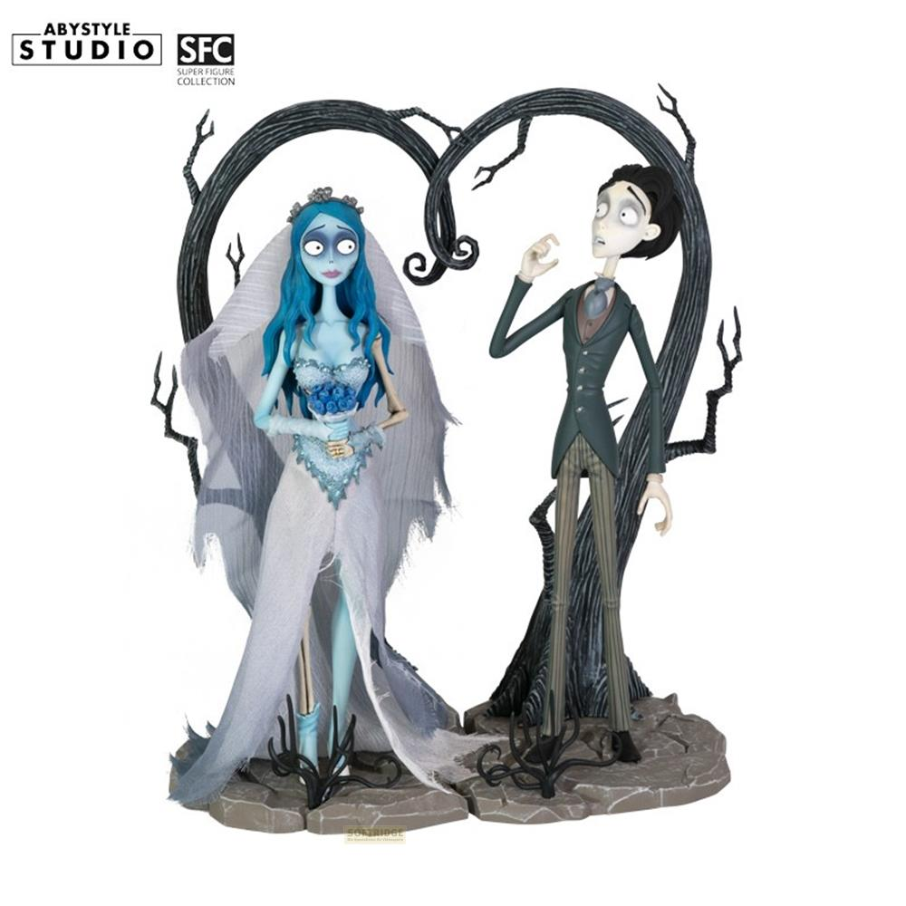Figuren von Braut und Bräutigam vor einem Baum in Herzform.