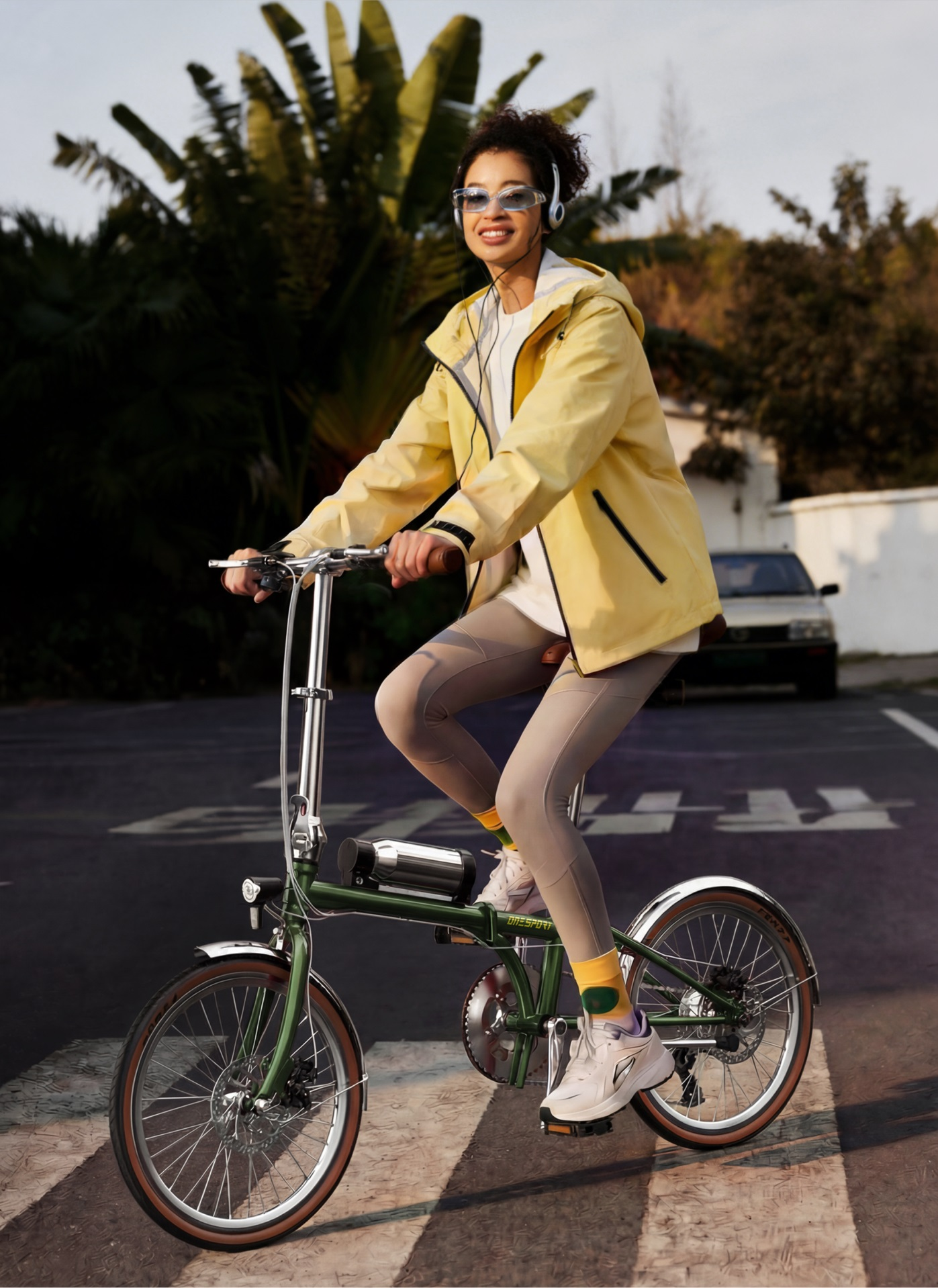 Una donna con cuffie guida una bici pieghevole per strada.
