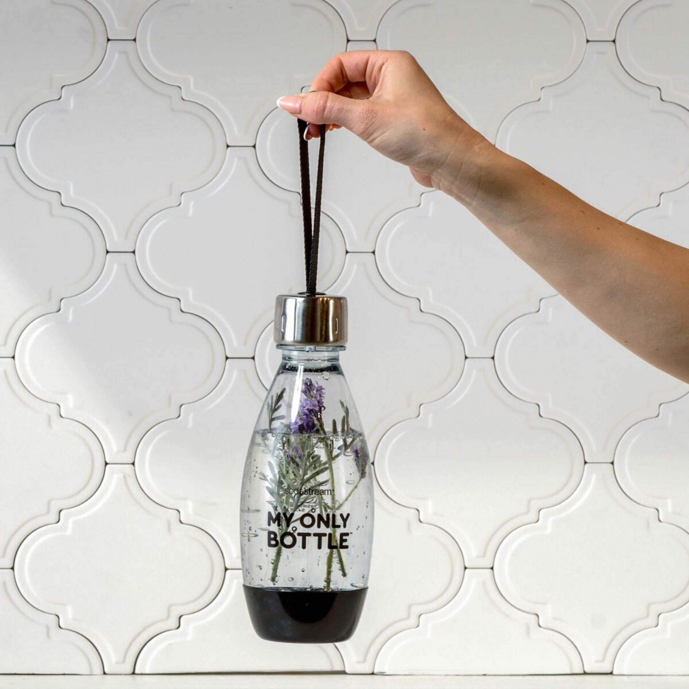 Una mano tiene una bottiglia SodaStream con lavanda e acqua.