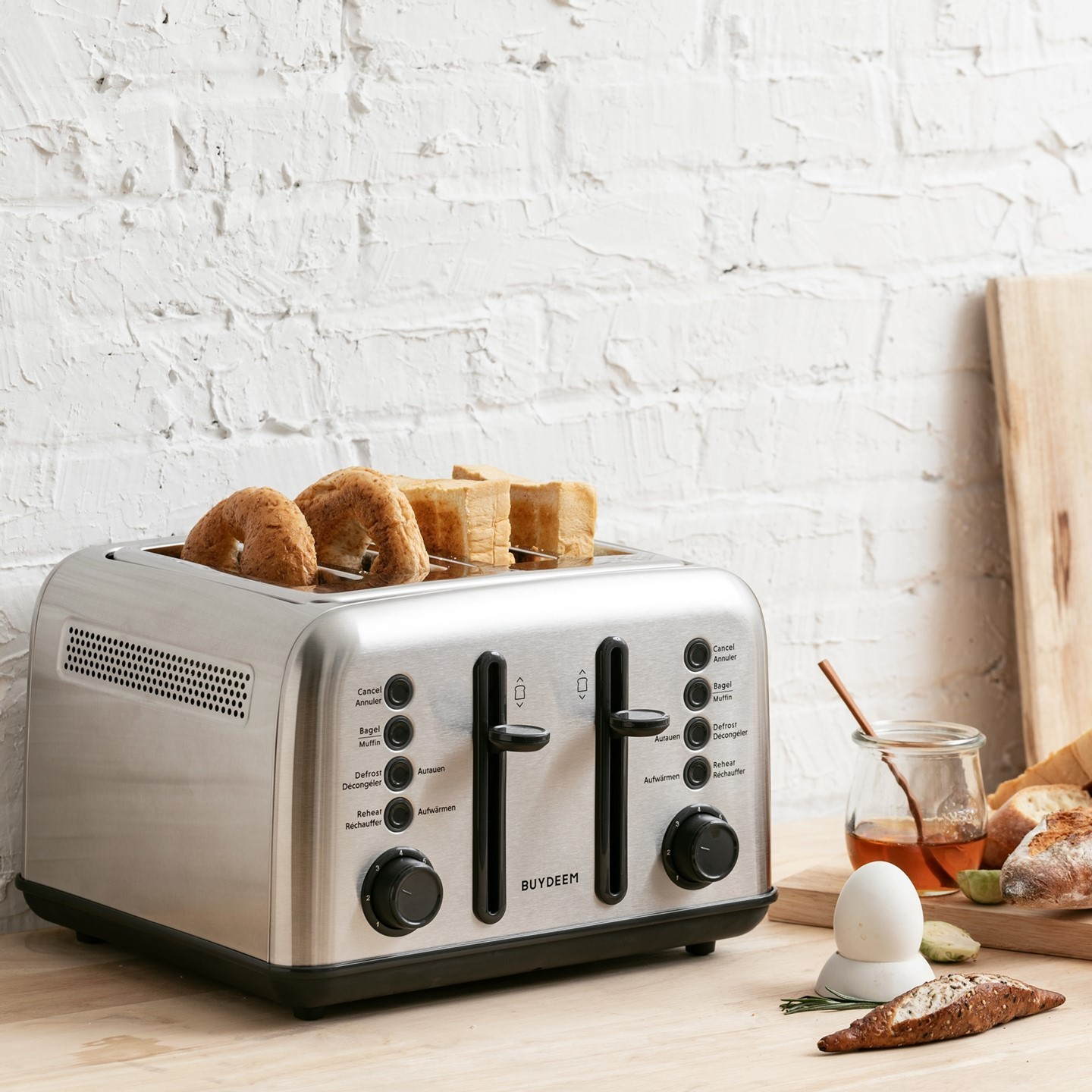 Srebrny toster na cztery kromki tostuje bajgle i kromki chleba na drewnianym stole.