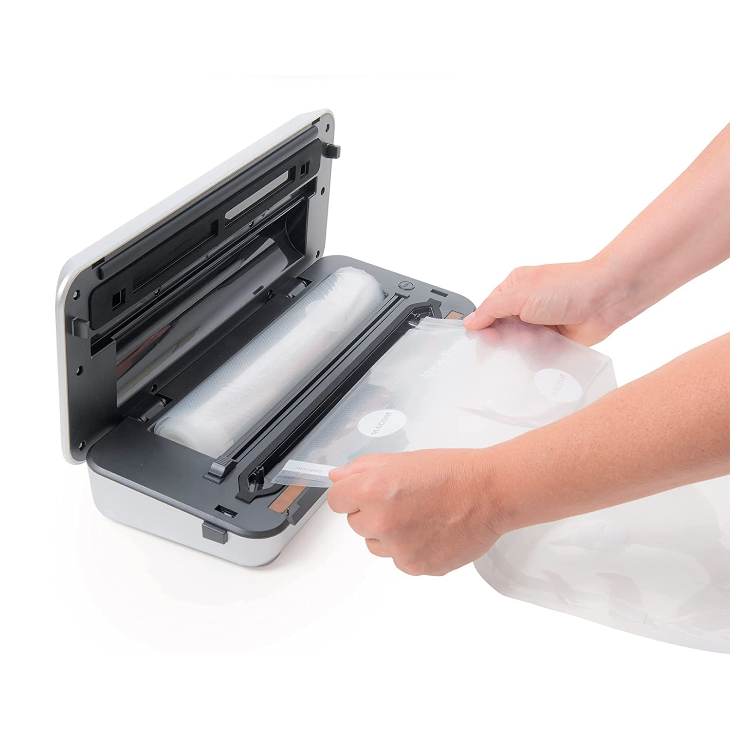 Una mano inserisce un sacchetto sottovuoto in una macchina sottovuoto aperta con rotolo.