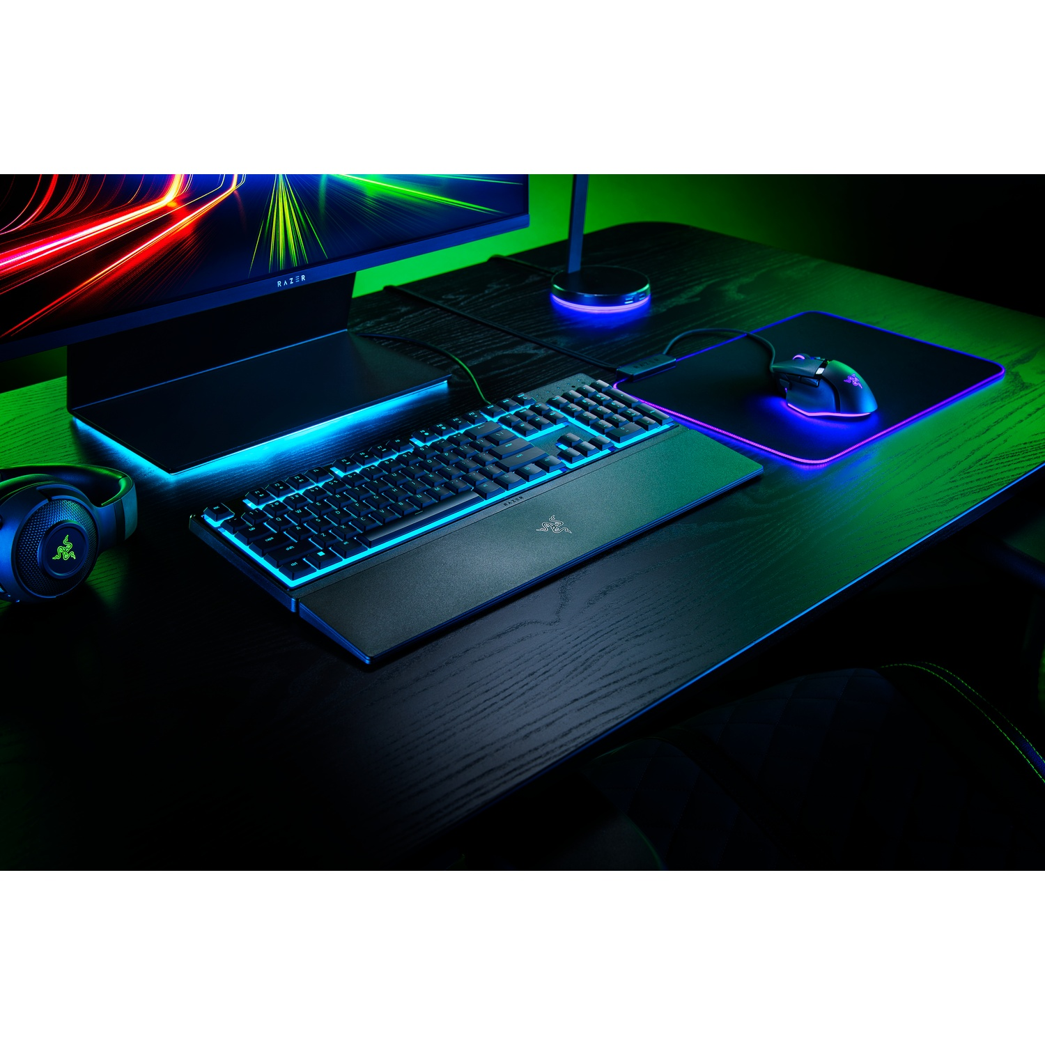 Czarny zestaw biurka gamingowego Razer z monitorem, klawiaturą, myszą i słuchawkami.