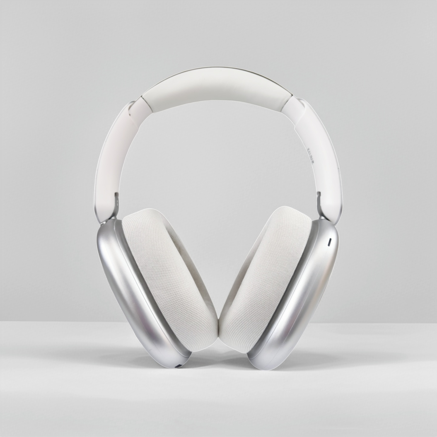 Auriculares blancos supraaurales con orejeras plateadas sobre fondo blanco.
