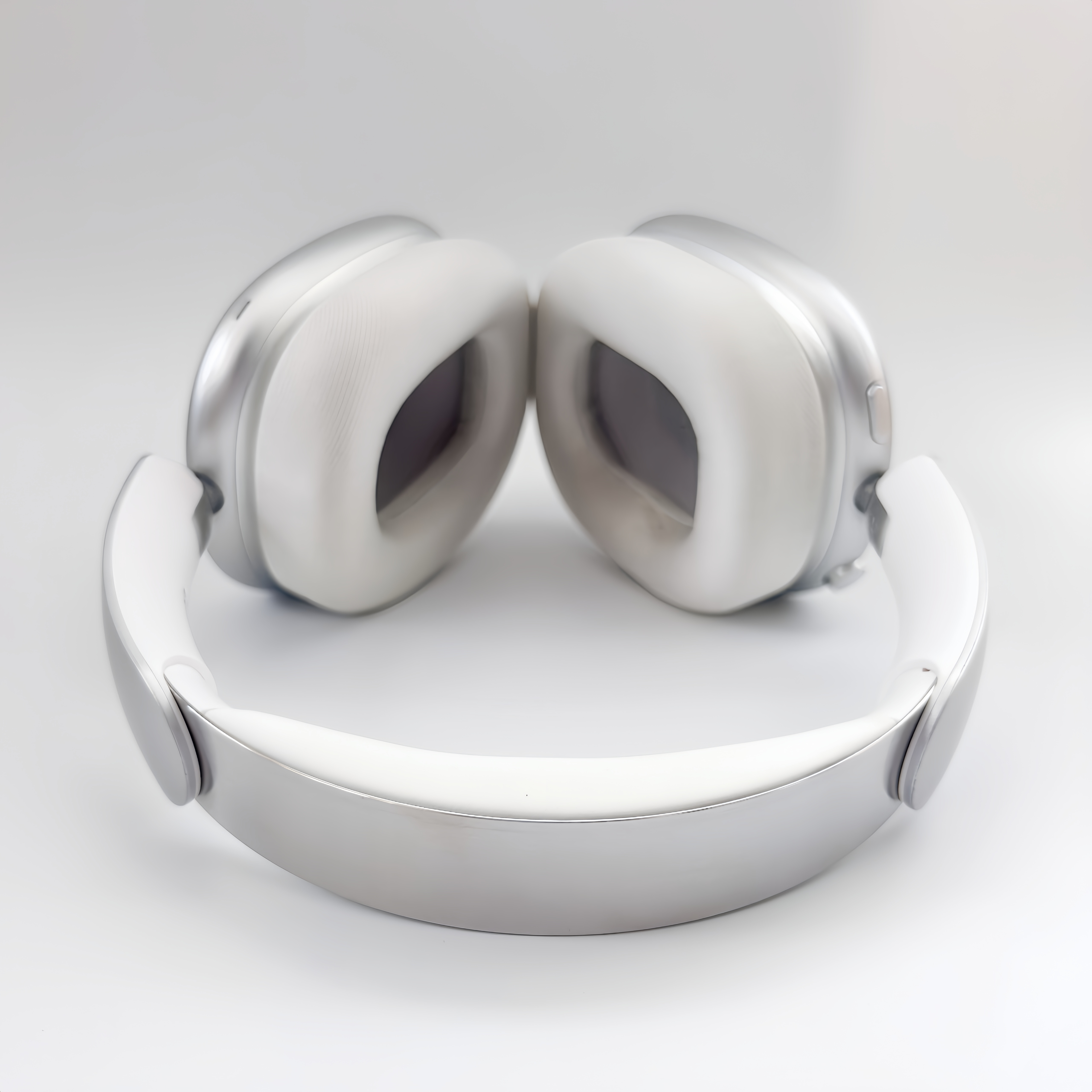 Auriculares plateados con almohadillas blancas sobre fondo blanco.