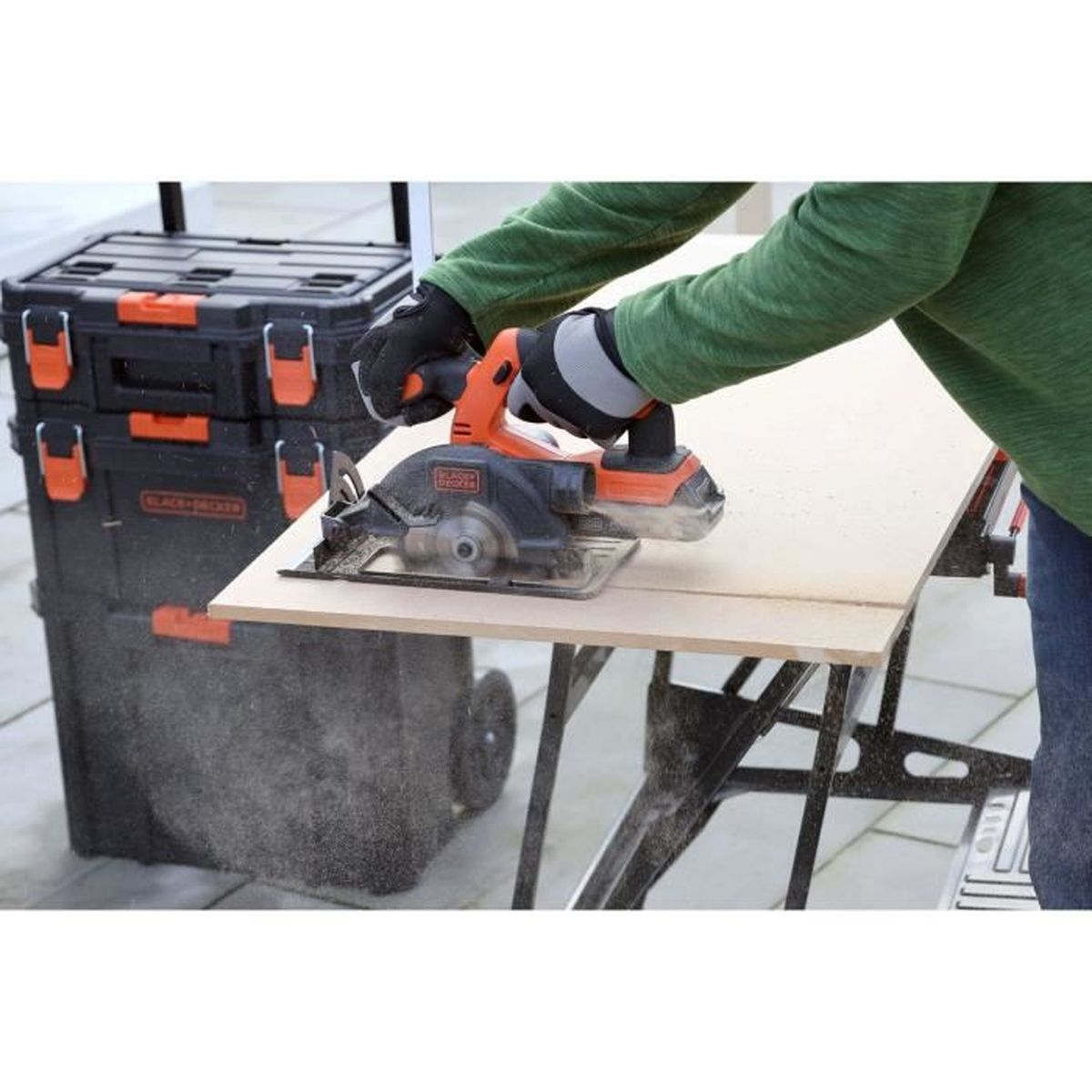 Osoba piująca drewno piłą tarczową. Czarna skrzynka narzędziowa w tle.