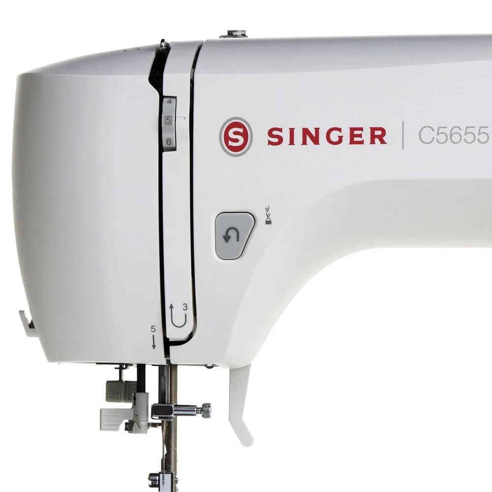 Dikiş ayarları ve iğnesi olan beyaz bir SINGER C5655 dikiş makinesinin yakın çekimi.