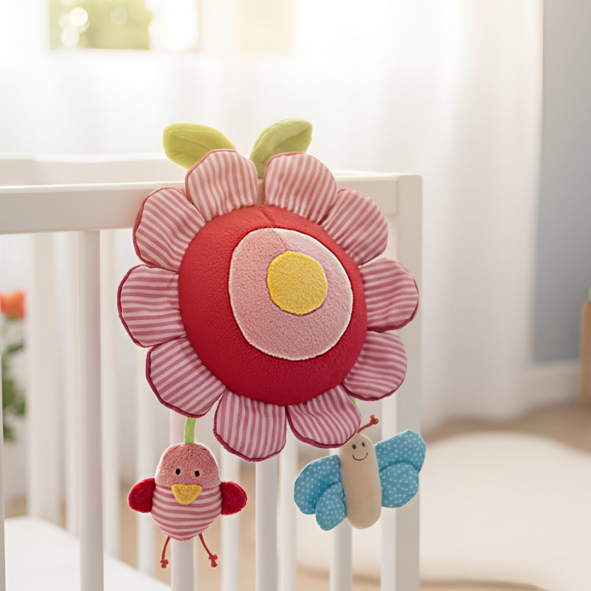 Un carillon di peluche con motivi floreali, uccello e farfalla pende da una culla.