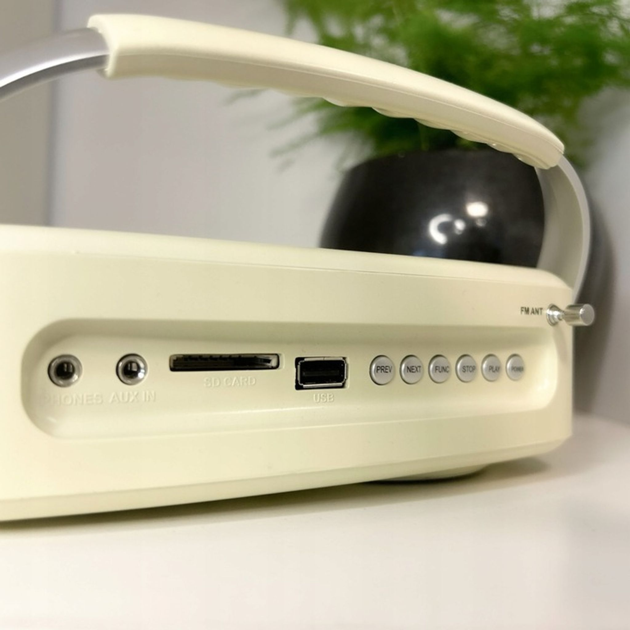 Kremowe radio z portami, przyciskami i anteną FM.