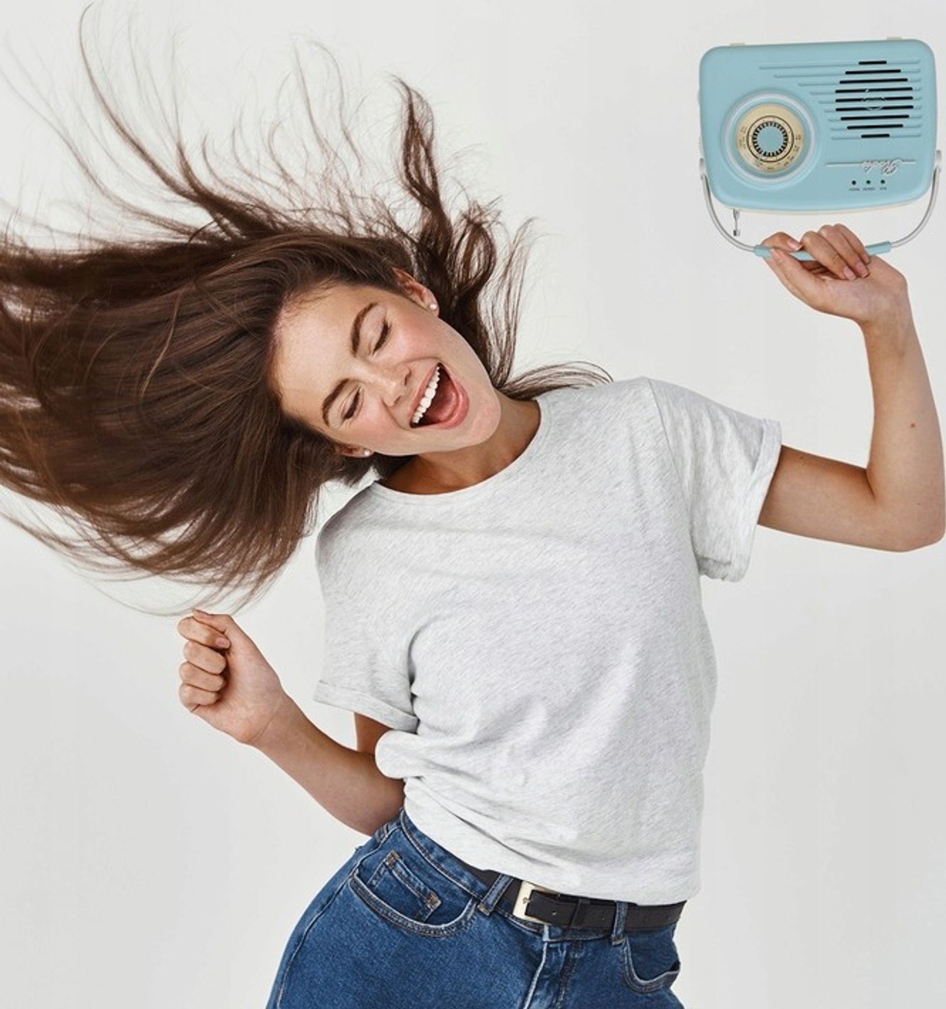 Kobieta z brązowymi włosami tańczy i trzyma niebieskie radio.