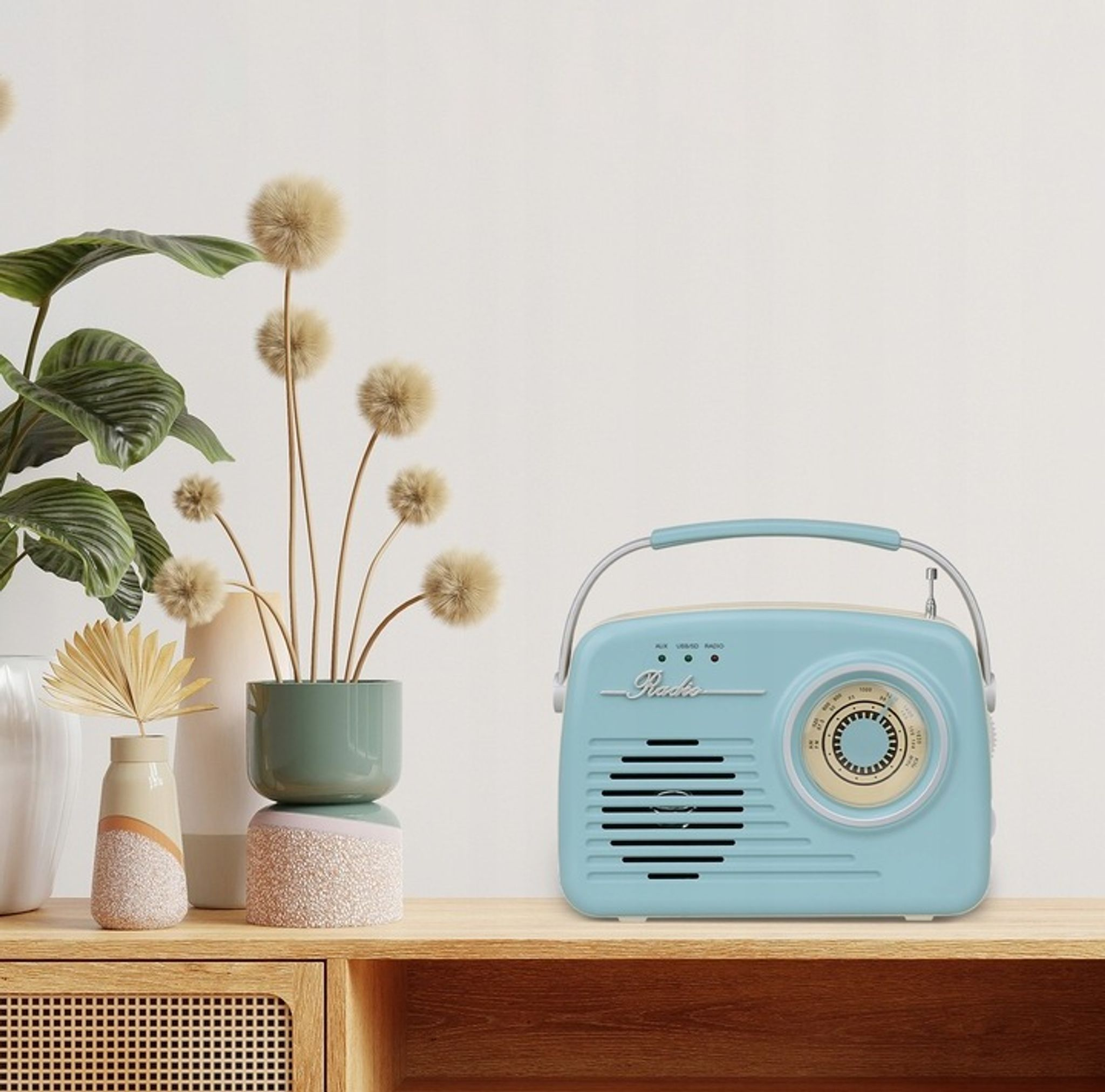 Jasnoniebieskie radio retro stoi na drewnianej półce obok roślin i wazonów.