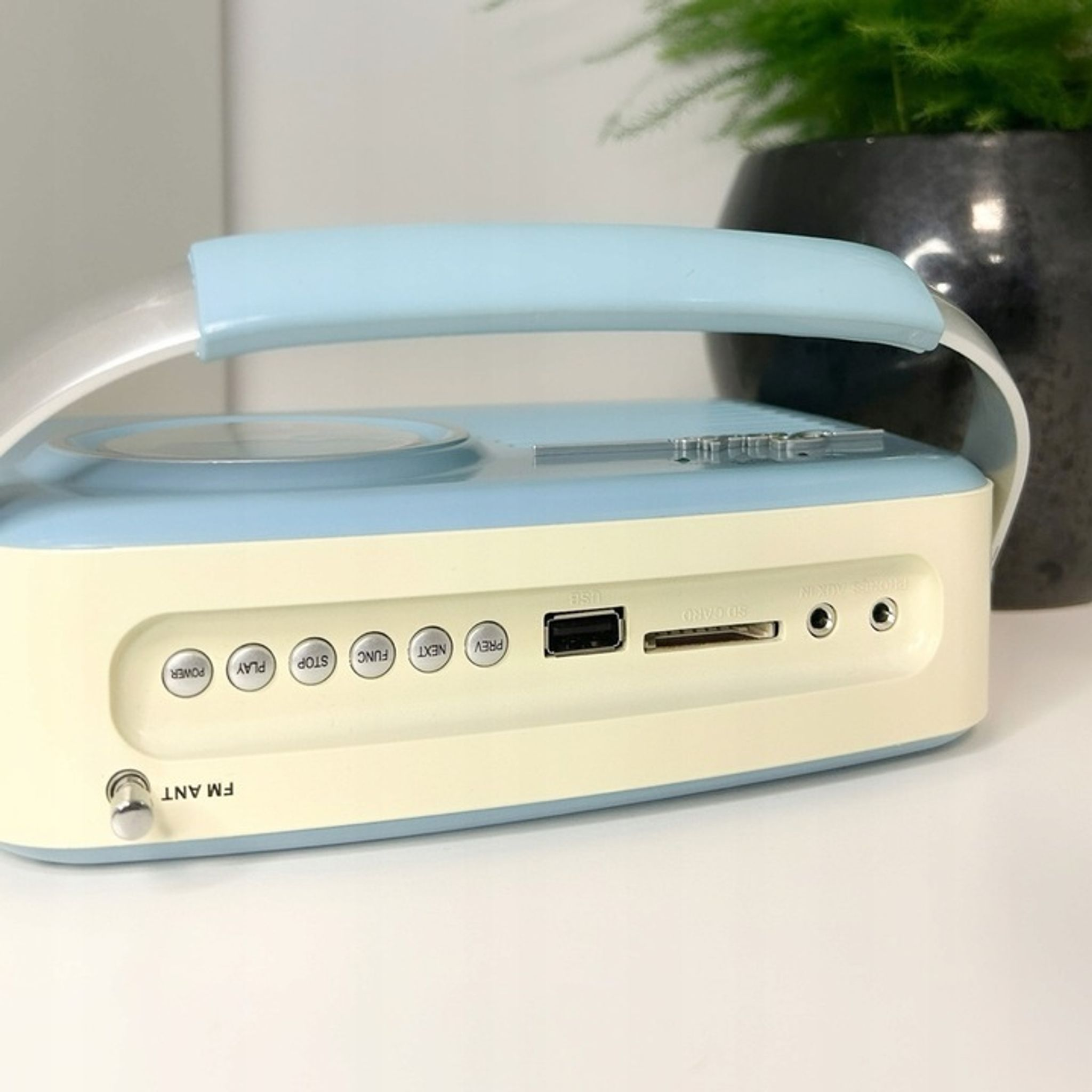 Jasnoniebieskie i kremowe radio przenośne z przyciskami i portami.