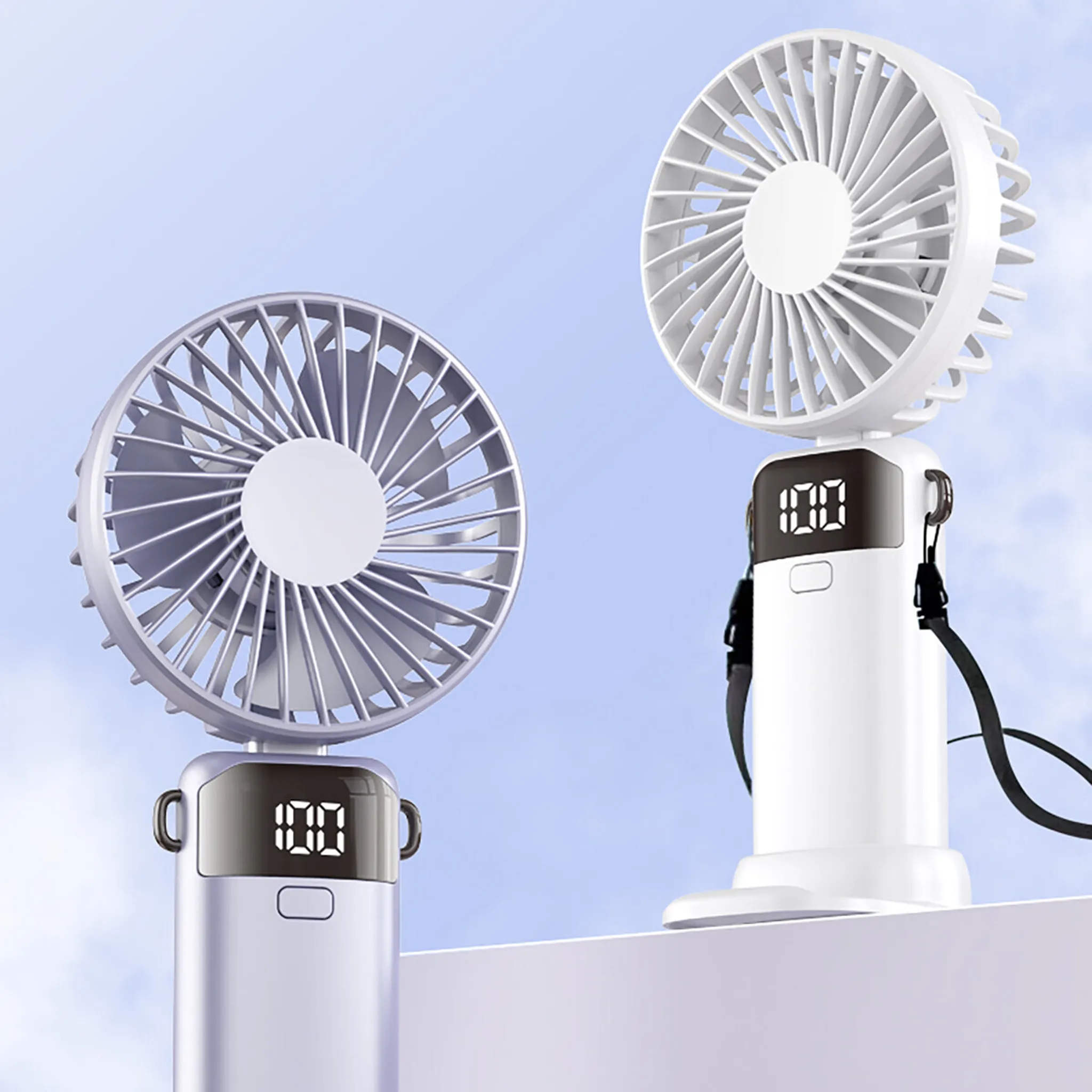 Zwei weiße Handventilatoren mit digitalen Displays stehen vor blauem Himmel.