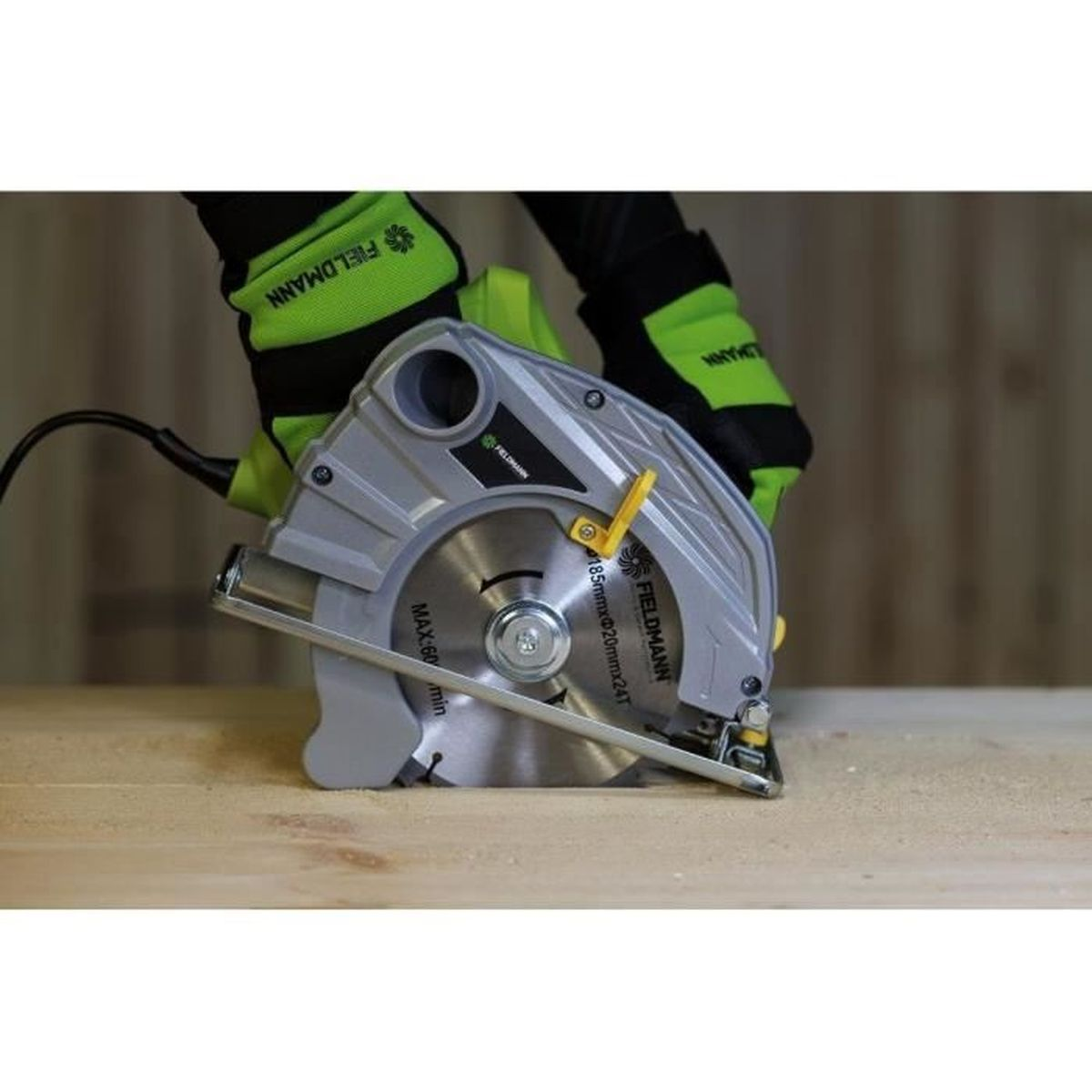 Dłoń w zielonej rękawicy trzyma piłę tarczową nad drewnem.