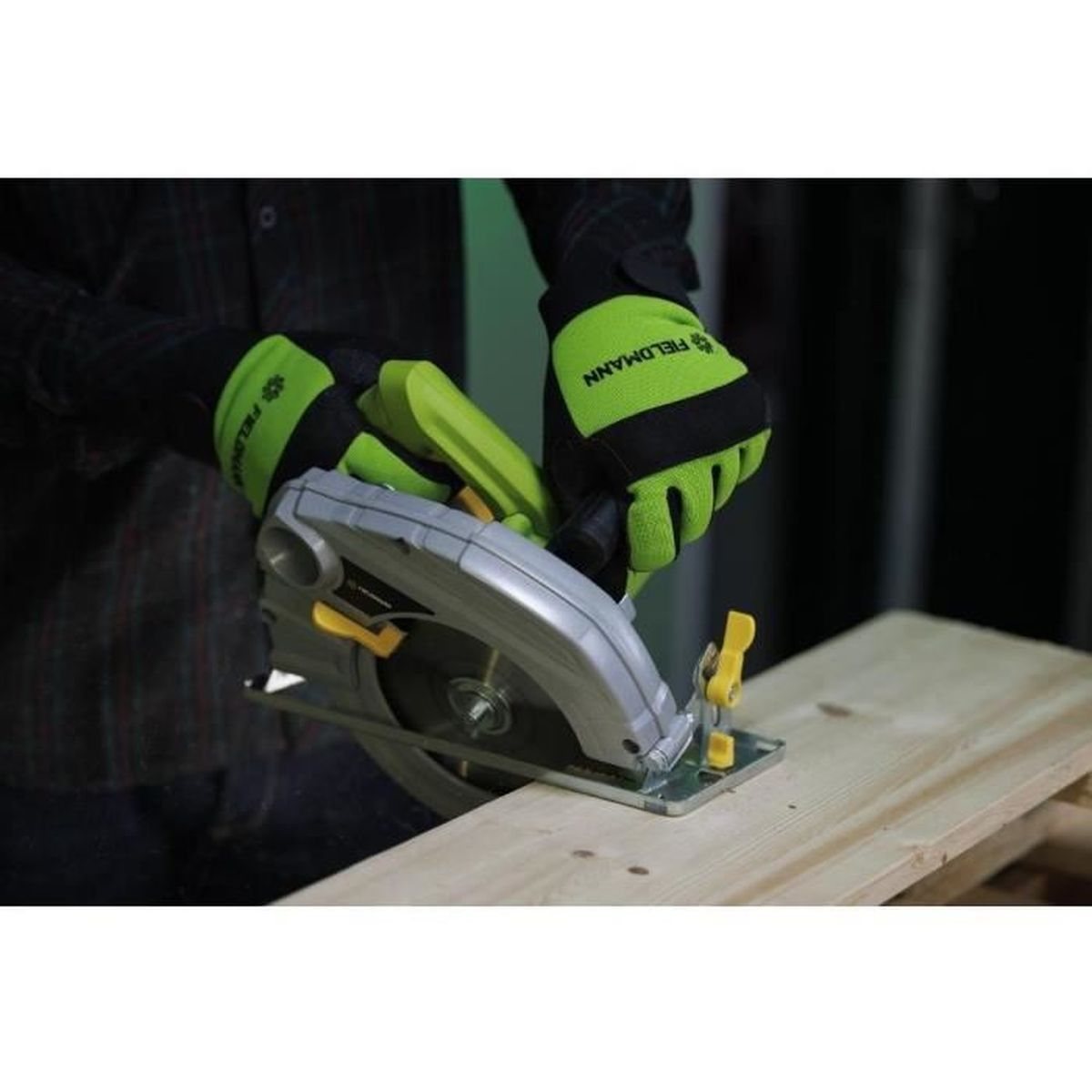 Osoba w rękawicach używa piły tarczowej na drewnie. Zielone rękawice z czarnym napisem.