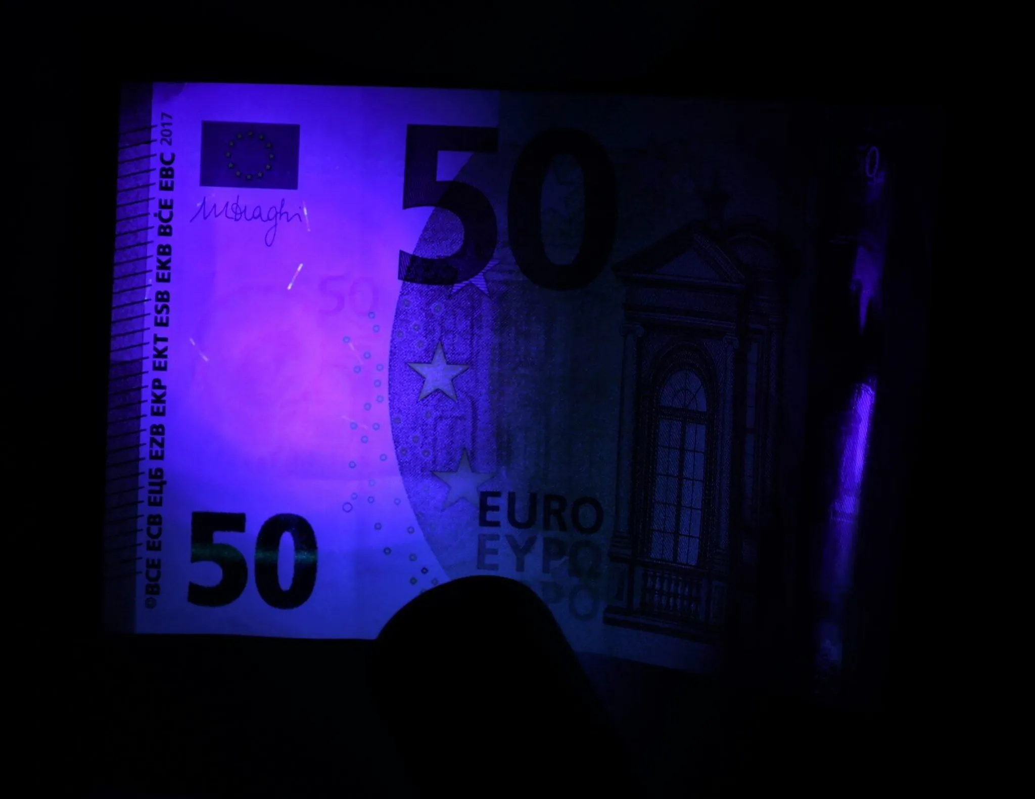 50-Euro-Banknote unter UV-Licht mit sichtbaren Sicherheitsmerkmalen.