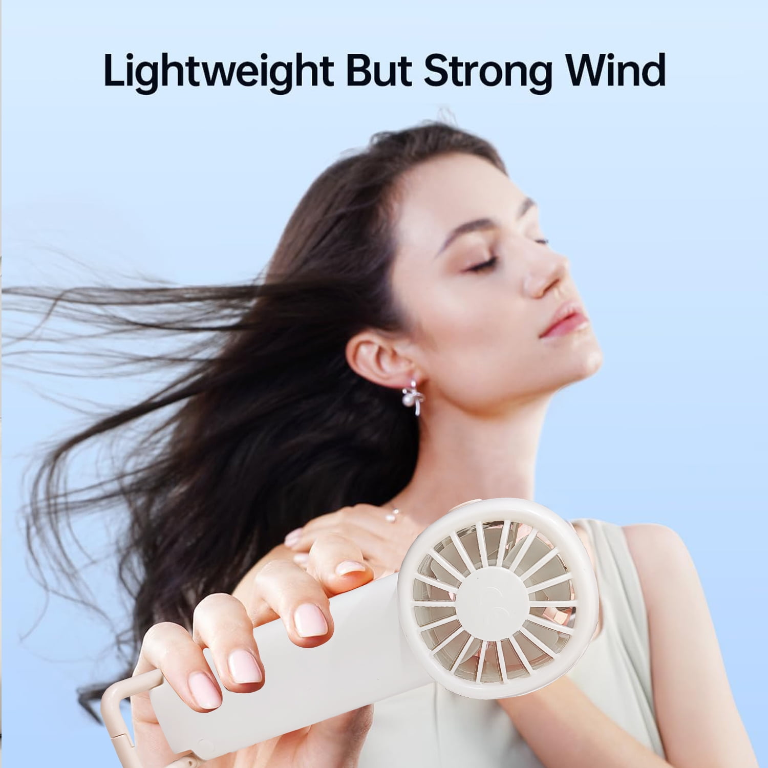 Eine Frau hält einen weißen Ventilator, ihr Haar weht im Wind.