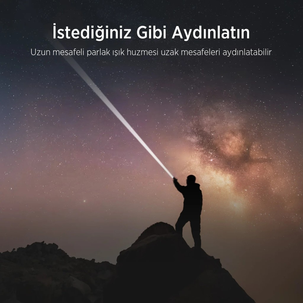 Kaya üzerinde duran silüet, ışık huzmesini yıldızlı gökyüzüne tutuyor.