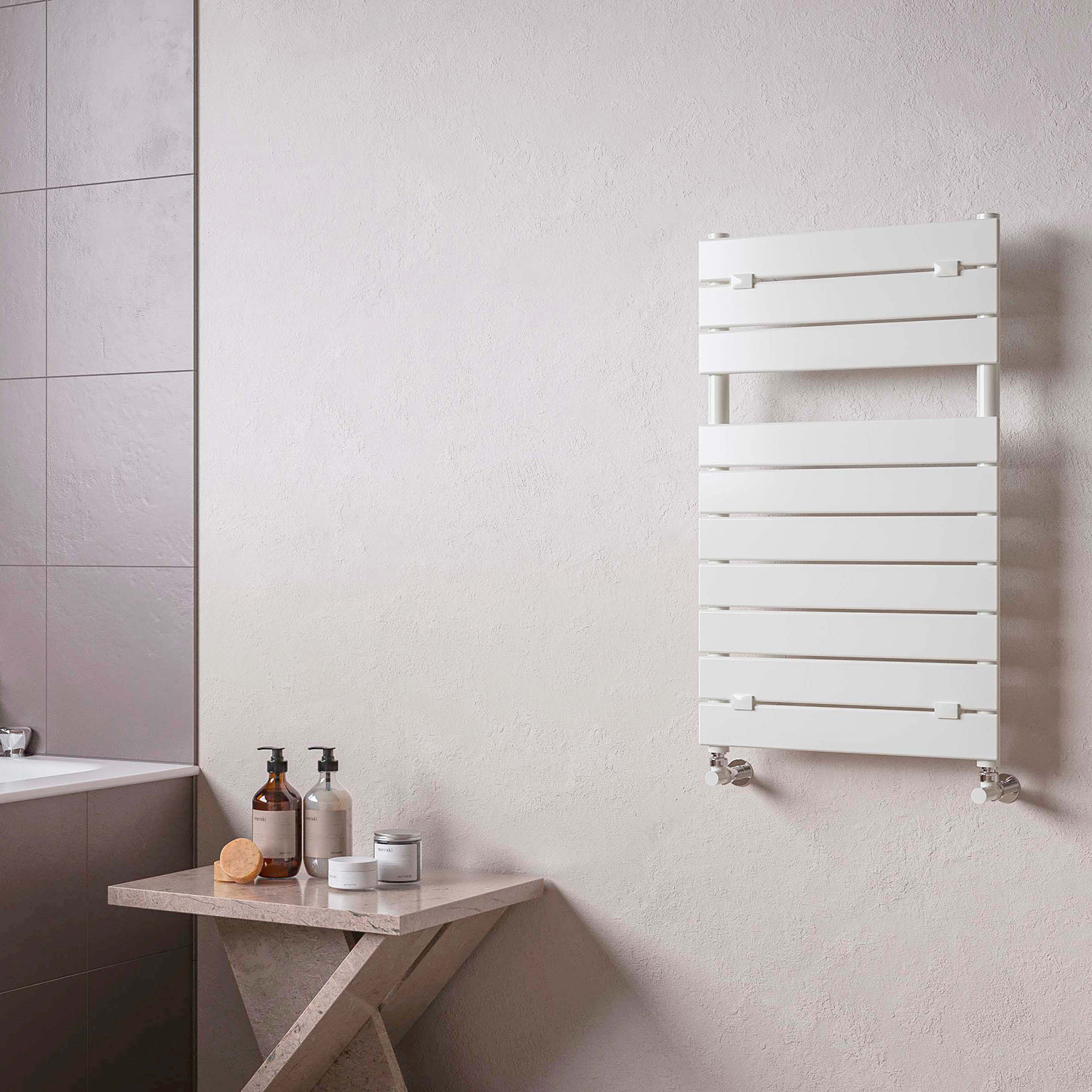 Un toallero blanco cuelga de una pared texturizada. A la izquierda, una mesa con jabón y dispensadores.