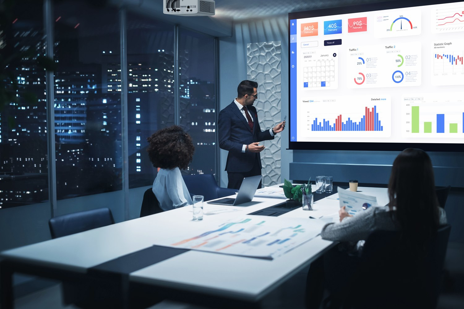 Mężczyźni prezentują dane finansowe na dużym ekranie w ciemnym biurze.