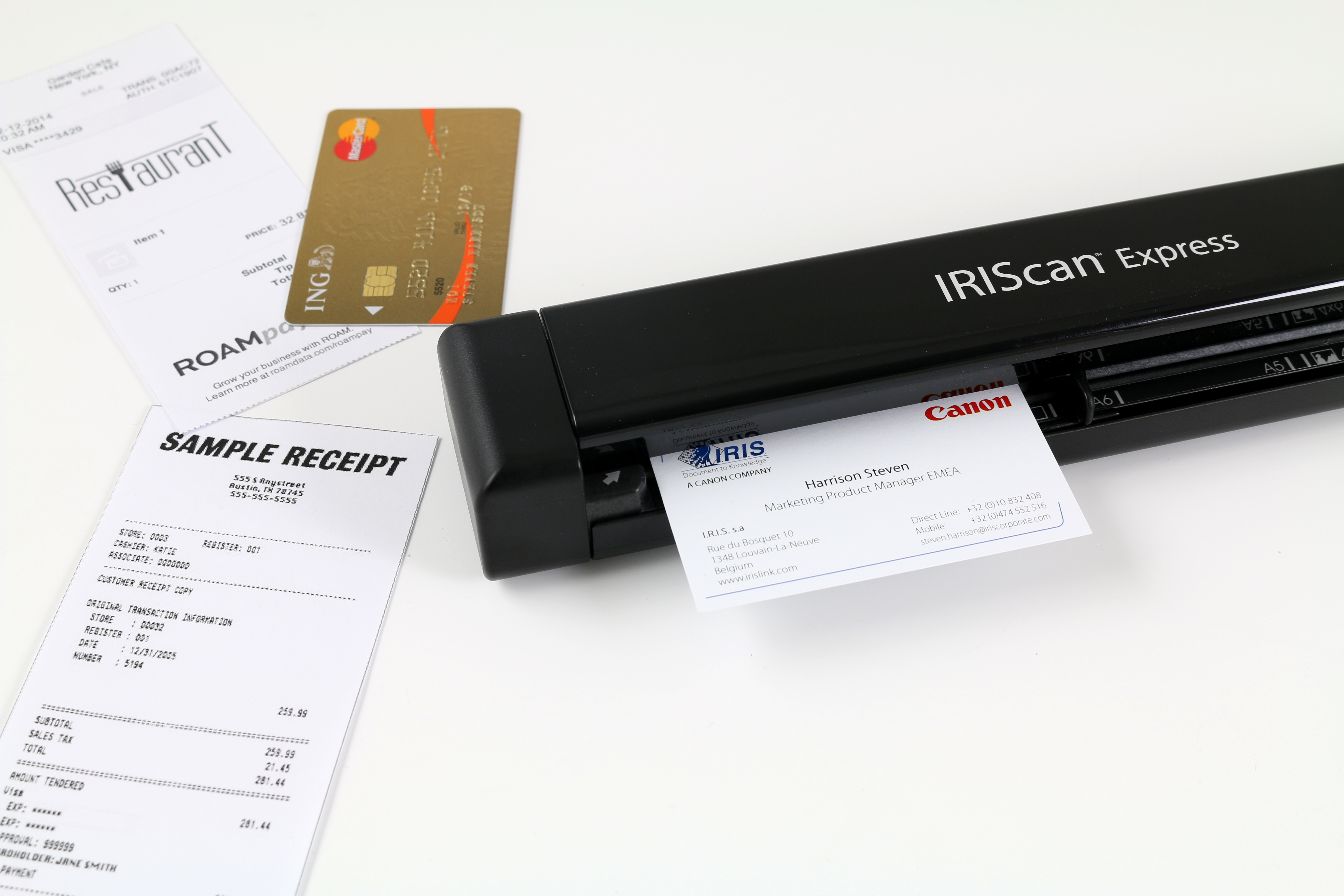 Ein IRIScan Express Scanner scannt eine Visitenkarte. Ein Beleg und eine Kreditkarte liegen daneben.