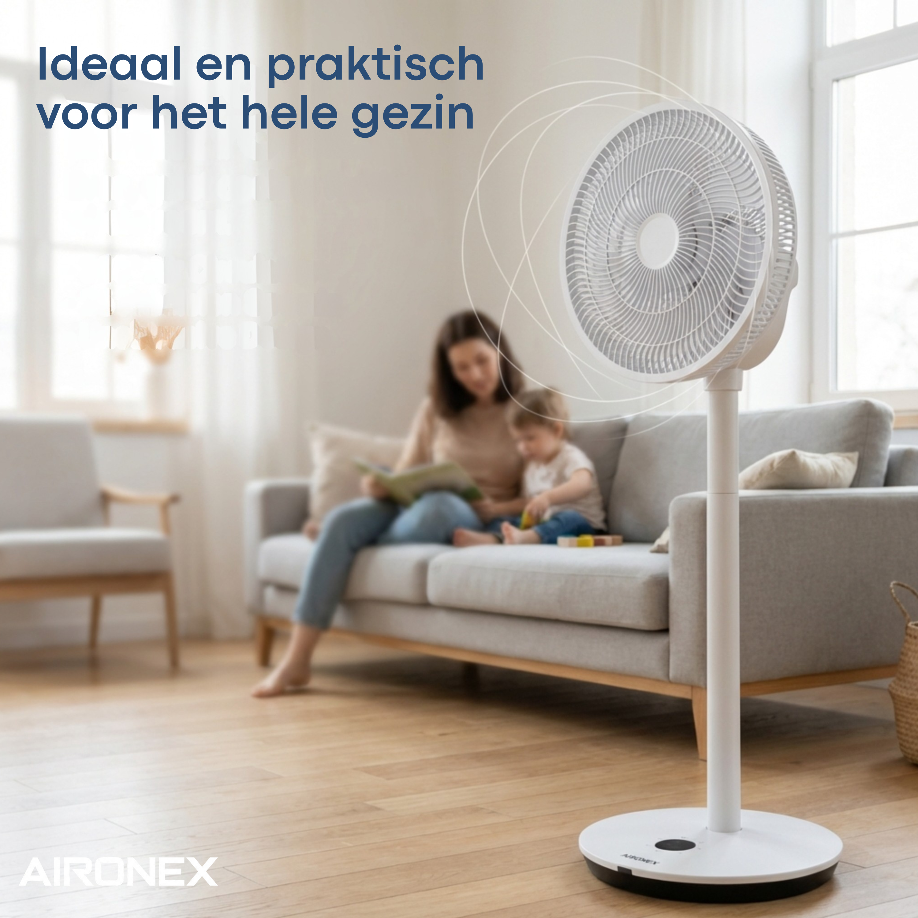 Ein weißer Standventilator steht auf einem Holzboden, im Hintergrund sitzt eine Mutter mit Kind auf einem Sofa.