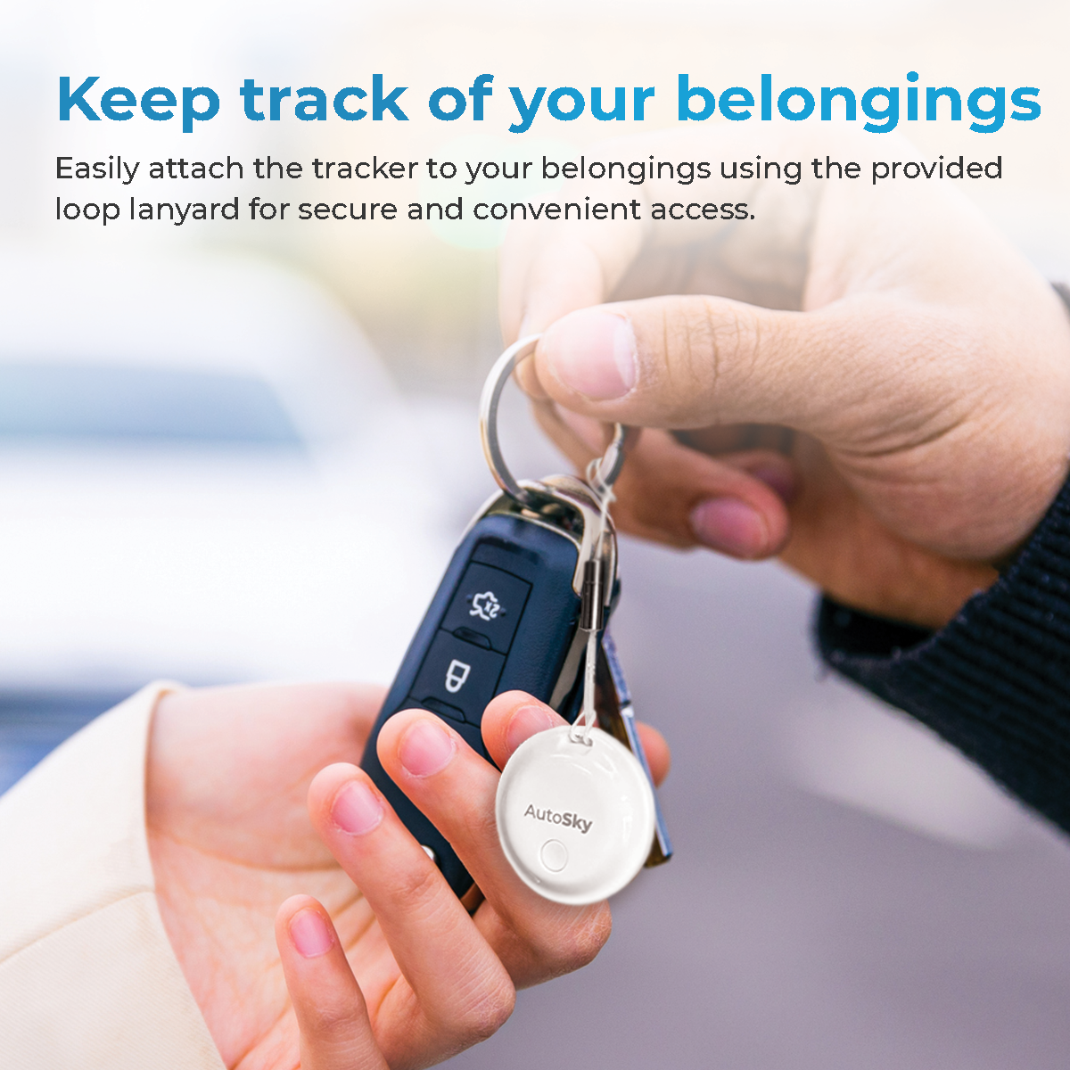 Una mano tiene chiavi dell'auto con un ciondolo tracker bianco.
