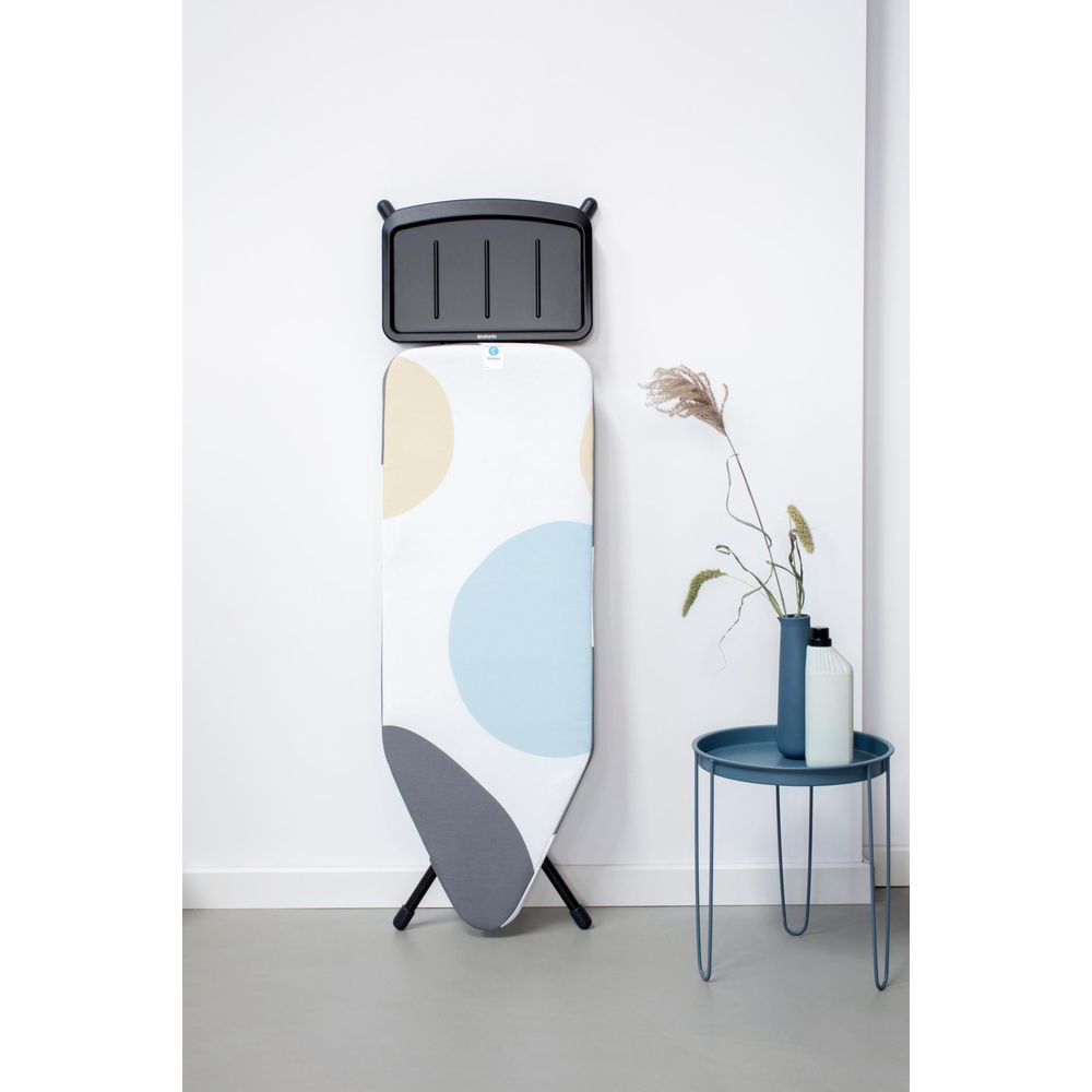 Strijkplankhouder aan muur boven strijkplank met cirkels.