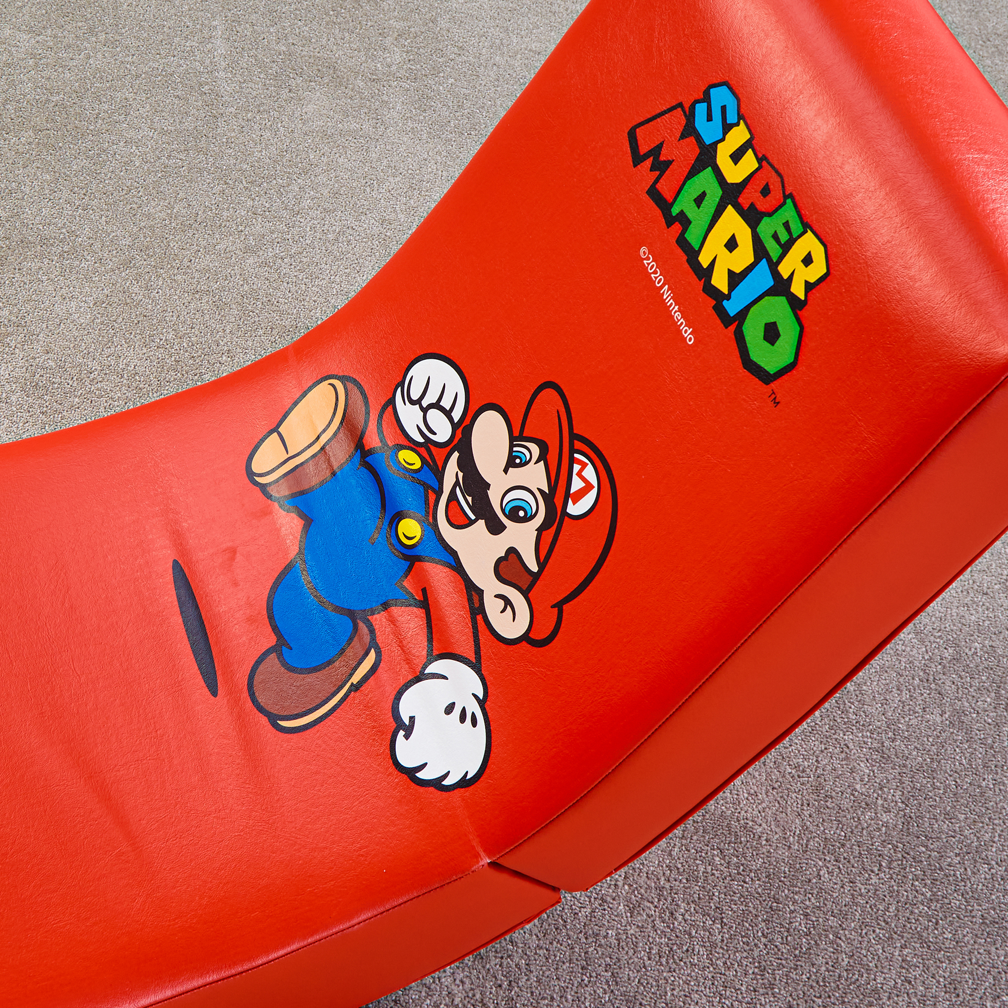 Mario sitzt auf einem roten Sitz mit dem Super Mario Logo und Nintendo Copyright.